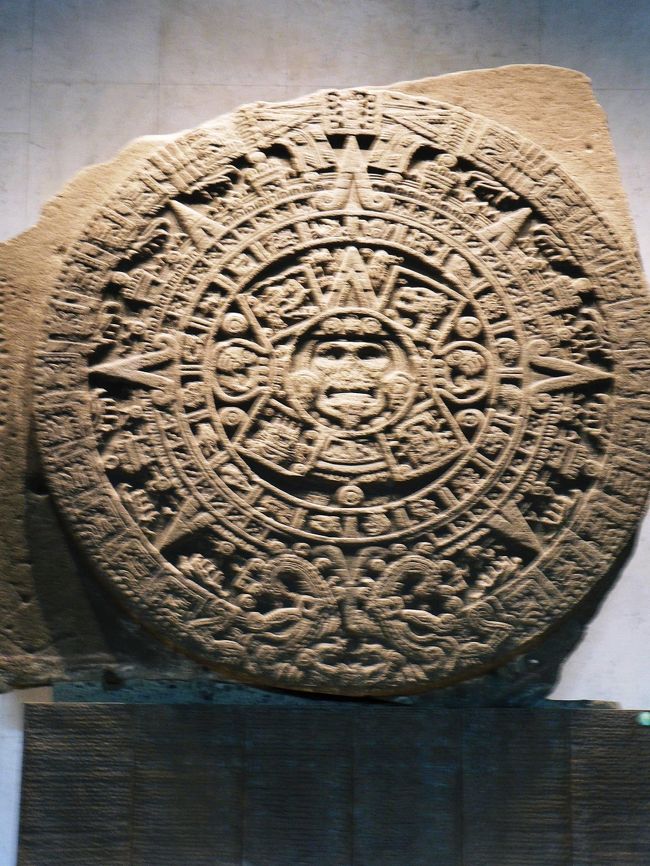 メキシコシティの国立人類学博物館は世界でも有数の規模と内容を誇っている。テオティワカン、マヤ、アステカなどの遺跡からの発掘物の中で特に保存すべき重要な物を展示している。その中でも最も有名な発掘物が　太陽の石「アステカ・カレンダー」だろう。直径３．６ｍの円盤には中央の太陽神の周りに複雑なモチーフが施されている。文様は宇宙が今まで経て来た４つの時代を示し現在は中央にある５番目の太陽トナティウ時代という。カレンダーは１年３６５日を正確に示しており、アステカ人は暦に従い農耕と生け贄の儀式を行っていた。アステカ帝国崩壊後、スペイン人はこれを捨て去ることを指示したが１７９０年に発見され、インディオの人達に大切にされていた。太陽の石は現在の太陽トナティウ時代は２０１２年１２月２３日に滅亡すると予言しているそうだ。アステカ文明は非常に高度な天文学を持っているだけに、何とも不気味な予言ではある。<br />（写真は太陽の石「アステカ・カレンダー」）