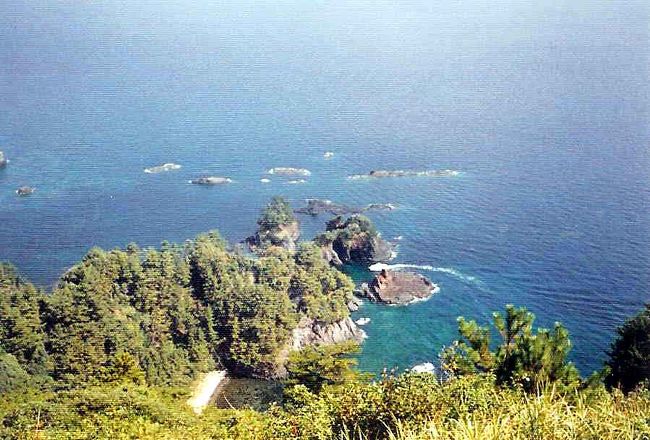 隠岐島(おきのしま)は、日本海に浮かぶ島根県所属の島々。島根半島から北東へ約65km、日本海に浮か島ぶ隠岐諸島は大小180余りの島々から成り立つ群島型離島である。島前(どうぜん)と呼ぶ3島・西ノ島、中ノ島、知夫里島、島後(どうご)の4島に約3万人が生活している。「竹島」(韓国名・独島)は1905年(明治38年)から島根県隠岐島の所管であったが日本の敗戦後、1952年(昭和27年) 韓国大統領・李承晩の海洋主権宣言(李承晩ライン宣言)による領有主張から問題が発生し、現在最大の日韓問題となっている。「竹島」は、現在も日本では島根県隠岐郡隠岐の島町に属しており、隠岐島の北西約157kmに位置し、東西の2主島と数十の岩礁から成り、東京ドームの約5倍の広さ。島は飲料水にも乏しく人の常住には適さず、最近韓国が警備兵を常駐させているそうだが古代より無人島だった。魚介藻類など水産資源が豊富で経済水域200海里が明文規定された後は重要性が高まり、水産資源の確保の観点から日韓の争点になっている。竹島は古代より日韓ともに漁場の普通の無人島だった訳だが漁場争いで重要になったと言えるだろう。これは住民が追い出された北方領土とは事情が異なる。日韓両国とも領土の主張をまげることは無いだろうが、この領域は公海にするなどの妥協点が無いものだろうかと思う。 一方、隠岐島は古代から防衛上の重要拠点とされ、島でありながら、淡路、佐渡とともに「国」として扱われてきた。また、この島は流刑の島として、承久の乱を起こした後鳥羽上皇(1180−1239年)、倒幕に失敗した後醍醐天皇(1288−1339年)を始め、遣唐副使小野篁、前加賀守源頼房等、都の貴人、高官が多数配流された島でもある。 特に有名なのは隠岐島脱出に成功し「建武の中興」を成立させた後醍醐天皇と倒幕に失敗して流された後鳥羽上皇だろう。上皇は脱出を諦め逝去までの16年間を隠岐で暮らした。藤原定家をも凌ぐすぐれた歌人と言われている。人もをし 人も恨めし あぢきなく 世をおもふゆえに 物おもふ身は 後鳥羽上皇この歌は百人一首で親しまれているおなじみの歌で上皇の無念さが良く伝わってくる。 島後では後醍醐天皇行在所といわれる隠岐国分寺(黒木御所説もある)と後鳥羽上皇を慰めるために始められ現在に至る牛突き、隠岐国の総本社玉若酢命神社、億岐家、樹齢2000年の八百杉、紺碧の日本海が鮮やかな白島海岸など、島前・西ノ島では国賀海岸、黒木御所などを観光したが、歴史・文化・自然ともに豊かな島だった。(写真は白島海岸の光景)