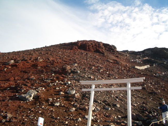 下山し始める頃には、周囲はすっかり明るくなっていた。登山道も明るいと、こうも印象が違うものなのか。そして、体を降ろすというのは、登らせるよりこんなに楽なものなのか。<br /><br />まだまだ空気は薄いはずなのに、9合5勺までの道で、休憩を取ったのはわずかに1回だった。途中途中で行きでは撮れなかった写真を撮りつつ、程なくして9合5勺の山小屋にたどり着く。<br /><br />たったこれだけ下っただけなのに、空気が濃いと感じる。呼吸がすごく楽だ。しかも動き始めたせいか、寒さも和らいだ気がする。3人で、暖まったね、空気が濃いねと笑い合う。下山楽勝じゃん。<br /><br />と、思ったのが甘かったことはすぐに判明した。富士山は登頂で道程の半分と思えと言われている山なのだ。我々ごときがなめていい山ではなかった。<br /><br />確かに呼吸は楽になった。気温も上がってきた。しかし、足がすぐ痛くなってきた。膝、太股、足首。9合5勺から下り始めてすぐ足の痛みは出現し、順調に悪化してきた。<br /><br />この時になって、ようやく登りの段階で、すでに足を酷使していたことを実感したが、なにせ登りは全身疲労の方が強くて、足の痛みを意識するだけの余裕がなかったのだろう。空気が濃くなってきて、全身疲労の方が楽になってから、足の痛みが襲ってきたような印象だった。<br /><br />しかも、登りの時にもちらっと思った「この道帰りはどうやって下ろうか。」と思うような岩場がところどころにある。両手を使い、しゃがんで、ほとんど飛び降りるようにして降りる。よくこれで怪我人が出ないよなあ。…出てるのか？<br /><br />かと思うと、さらさらの火山砂のところでは、すべって転ぶ人が続出している。我々も最初はバランスを取ったり、杖を使ったり、登山道に張ってあるロープに掴まったりしてどうにか転倒を避けていたのだが、足の痛みと疲労が強くなるにつれて、小手先で転倒を避けることが難しくなった。3人とも、少なくとも1回ずつは思いっきり転倒した。<br /><br />まだ早朝だというのに、顔に照りつける日差しはかなり強い。「…ねえ、昨日の朝塗った日焼け止めって、効いてると思う？」「ううん、全然ダメだと思う。」リュックに入っているはずなのだが、出して塗り直す気にはならない。<br /><br />下りの道は、登山する人と下山する人が入り乱れて混んでいた。登りの時には人と人とのすれ違いの事なんか全く考えなくて良かったことを考えると、やはり夜登ったのは正解だったのかもしれない。なにせ、道が狭いので行き違いに気を遣うし、時間も使う。<br /><br />これからこの山のてっぺんまで登っていく人を見ると、なんとなく生暖かい笑顔になってしまう。元気な若者を見ても、「ここまでくれば頂上までもう少しよね！」と喋る女性を見ても、ついつい笑ってしまう。まだまだ頂上じゃないよー。きっと思ってたより大変だよー。頑張ってねー。<br /><br />しかし、我々もそこまでの余裕はないのであった。下山の道のりは延々と続く。行きと違って明るいし、かといって景色は代わり映えしないし、そのくせ下りの道はよく見えるし、次の山小屋までの距離が半端じゃなく遠く見える。<br /><br />あー、あそこまで言ってもまだ8合目なんだ。こんなに遠かったっけ？<br /><br />膝や足首の痛みはかなり強くなってきて、時々岩場で休憩を取らないと一気に下れない。登山中も頼りになった登山用ステッキだが、下山時には、頼りになるというより、ほとんどこれなしでは下れないぐらいだった。<br /><br />時にステッキに全体重を預けつつ、また山道に張ってあるロープに全身で頼りつつ、ひたすら下りに下る。しょっちゅう滑って体勢を崩す。こうなると、足だけではなく腕や腰まで痛くなってくる。つまり全身筋肉関節痛状態なのである。<br /><br />途中休憩の時の雑談で、友人に私が<br /><br />「富士登山初回での登頂率って、4割ぐらいなんだってね。」<br /><br />と話すと、疲労と足の痛みで（しかも転んで軽い怪我までしていた）限界という顔をしている友人が言った。<br /><br />「下山率は？」<br /><br />…どこに残るんだ、どこに？下山率が10割じゃなかったら、捜索隊が出るだろうが。<br /><br />「足が痛い。もう歩きたくない。他の方法で下山できるんだったら、絶対そうしてる。」<br /><br />いや、気持ちはわかるけどね。山小屋を過ぎて、次の山小屋の位置を見るたびにうんざりしてくる。下山を甘く見たなあ。登りで限界まで疲れた体を、同じ距離降ろして来るんだから、当然と言や当然なんだけど。ただ、疲労困憊にも関わらず、行きと違って気分不快がない分私としては下山の方がよほど楽だった。なにせ登りでは口にできなかったカロリーメイトがおいしいし。