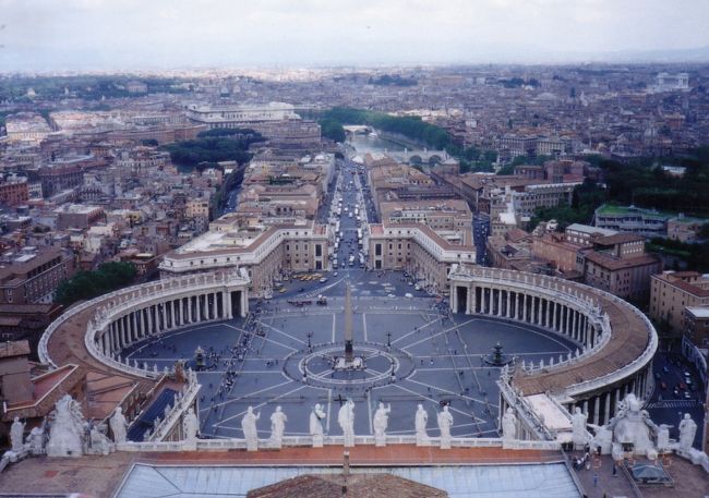 ローマは意外に小さい。バチカンには３度行って、１度目はバス、２度目は地下鉄、３度目はタクシー(朝８時頃に行った)だったが、次に行く機会があれば、やはりタクシーで朝早くに行きたい。テルミニからでも1万5千Lit、ヴェネチア広場からだと1万Litしかしないし、朝早くのサンピエトロ寺院は観光客が少なくて写真を撮りやすい。ただし、寺院内ではフラッシュ撮影は慎みたい。クーポラに上がるエレベーターも８時から営業している。(エレベーターは英語でliftと書いてある)<br /><br />  初めての時はローマを午前中だけでぐるりと回る観光バスを利用した。その時、最後に回ったサンピエトロ寺院に感動して、ここでツアーから離れてゆっくり回る事にしたのだが、肝心のヴァチカン博物館はガイドブックに13時までと書いてあったのに、11時で入場の列を締め切っていて入館出来なかったのだ。この時ばかりは再びローマにこれます様に願わずにはいられなかった。これに懲りて、イタリアで博物館にいくのは必ず午前中にする事にしている。<br /><br />  ２度目に行った時はまずヴァチカン博物館に入った。モデルコースが１時間半、３時間、３時間半、５時間コースと４つあって、その大きさにはとにかく圧倒される。エジプト美術館等を端折って見たとしても長時間だ。バチカンだけに日程に１日取っていて正解だった。実際、朝早くから出掛けたのだが、１時間近い待ち時間と見学２時間の後、ヴァチカン博物館とシスティーナ礼拝堂の間にあるカフェテリアに到着した時にはちょうど昼食時になっていた。ここで食事すると、安上がりの割にくつろげる。しかも足も疲れてきていて、ちょうど良い休憩時間だ。ただ、所詮はカフェテリアなので、注文したカプチーノはインスタントだった。<br /><br />  昼食時にバチカンから日本に電話しようとしたら、テレホンカードが使えなかった。まさかと思ったが、予想通りにバチカン市国専用のテレフォンカードが売られていて、これ以外は使えなかった。ただ、売られているのは3000Lit(当時の価値で150円)のカードだけで日本に電話するにはちょっと短すぎる。<br /><br />  バチカン博物館の収蔵物はすごいけれど、廊下部分のフレスコ画が素晴らしいのを除けば、美術に疎い私には数が多すぎて、かえって食傷気味になってしまった。しかし、最後はシスティーナ礼拝堂だけは特別で、それまでに見た物の印象が薄れてしまった。「さすが、ミケランジェロ」としか、私はこれを表現する言葉を持ち合わせていないし、美味しい食べ物を「まったりとして」なんて言ってみたところで、はて、まったりとしてとはどんな感じなのだろうか思う様で、書いても仕方がない気がする。とにかく、行って見てみよう。「さすが、ミケランジェロ」と思うかもしれない。<br /><br />  私は「アダムの創造」を見て、私たちはどこに行くのだろうか、神の手が届かなくなってしまって、これからどうすれば良いのだろうかと切ないような孤独を感じた。<br /><br /><br />  博物館で凝った肩や苦しくなった胸の為に最高の場所がヴァチカンに用意されている。それがクーポラだ。エレベーターで行くのと階段で行く方法があるが、悪い事は言わないから、7000Litを払ってエレベーターに乗ろう。エレベーターに乗っても、まだまだ十分過ぎるくらいの階段昇降運動が残されている。両親と入った時は既に2度目で、様子が分かっていたので、私は足の弱い母を下に置いて、歩いて登ろうと健脚を誇る父を説得してエレベーターに乗った。実際、父は下から歩いてこなくて良かったと納得していた。何しろ高さ132ｍ、マンションで言えば40階分の高さを擦り減った石段や窮屈な螺旋階段で上らなければいけないのだ。エレベーターを使っても、寺院本体の屋根の高さ迄なので、ここからクーポラの頂上まではかなり歩く事を覚悟しておこう。<br /><br />  寺院の外側(祭壇右手)から乗ったエレベーターが着く場所は寺院の屋根の部分だと思うが、ここにはバチカン直営の土産物屋さんがあって、シスターが売り子をしている。10年ほど前に日本人のシスターがここで働いている事が新聞に載っていたが、８年前には本当に会えた。しかし、今はどうしているのか判らない。<br /><br />  クーポラの上からは下の写真の様にサンマルコ広場が見渡せる。バチカンだけではなくローマ市内全域が見渡せるから、高いところが好きな方には見逃せない場所だ。ただし、日没時までしか開いていないので、夜景を楽しむと言う訳にはいかないようだ。<br /><br />  エレベーターで降りると寺院の中で祭壇左手に出てくる。寺院の中を見まわすと、いつでも聖ピエトロ像の前に人だかりができていて、皆が像の足をさすったり、キスをしたりしている。年月とは凄いもので、このキスの為に足の小指が半分近く溶けてなくなっている。ここに溶けるような熱いキスは実在したのだ。(なんか違うかな)