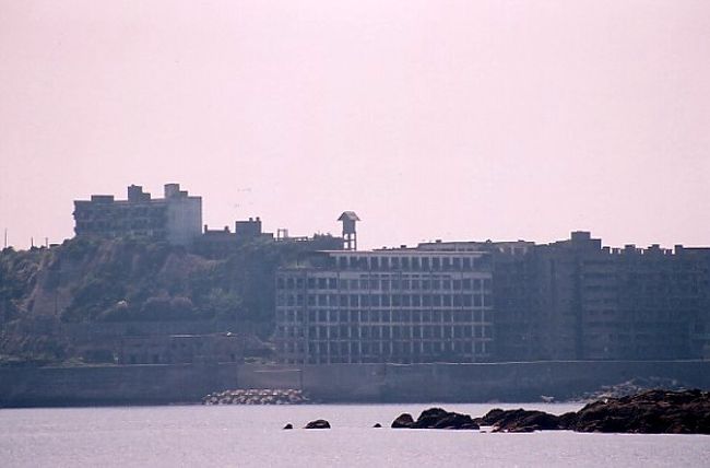 かつては人口密度世界一としてギネスブックにも登録された端島（はしま）。長崎の沖にあるその島は、その姿が戦艦に似ていることから「軍艦島」とも呼ばれていました。<br /><br />エネルギー資源として炭鉱が脚光を帯びてきた1915年以降、高層アパートが次々にこの島に建造され、ピーク時には5000人もの住人がいました。やがて時代の流れの中で、1974年閉山し誰も住まない無人島になってしまいました。<br /><br />480ｍ×160ｍの小さい島でありながら、高層建築が建ち並ぶ軍艦島。今回、クルーズ船に乗って海上から撮影することが出来ました。かつての面影が廃墟の中から浮かび上がってきます。<br /><br />また長崎滞在中に、偶然ですが、１８歳までその島で暮らしていたという人から話を聞く機会がありました。今では当たり前となったテレビや水洗トイレも、実は長崎市内よりも軍艦島のほうが、普及が早かったそうです。それくらいかつては繁栄と活気のある島だったそうです。