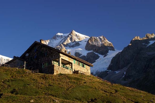 ヨーロッパアルプスのトレッキング（途中泊のあるハイキング）ではオートルート、ツール・ド・モンテローザなども人気があるが、ツール・ド・モンブランが一番歴史があり、規模も大きく最も人気がある。<br />このコースはモンブランの周囲の山をシャモニーからフランス、イタリア、スイスと（正確にたどると）距離158km 標高差合計8500mを歩く。しかし通常は（特にツアーでは）谷間の自動車道は景観も劣ることもあって部分的にバスを利用することが多い。<br />後述するが連続する山小屋泊まりと登り降りが続くので中級クラスと位置づけてツアーでないといけないコースとする雰囲気が日本では濃い。<br />そのようなコースを一人で歩くことにしたのは<br />1.74歳の年相応の体力と写真撮影を考えると歩く速度が遅くてツアーの皆さんに迷惑をかけるおそれがある。<br />2.ツアーのルートでは私が行きたい所（モンブランのイタリア側の展望台ラルプ・ヴィエイユからシュクルイ湖までの高原ルート）を省略するし、反対にシャンペから後半のように既に歩いていたり興味のない所が含まれている。<br />3.個人ならスケジュールが自由だから、雨が降れば小屋で晴れるのを待つことができる。小屋と小屋の間隔は数時間ぐらいと短いので安心だ。<br />などが理由だ。<br />単独行のために準備したのは<br />1. 体力を考えて荷物は30リットルのリュックに入るだけに制限する。写真用具では三脚はやめたがカメラは予備を入れて2台となり、いきおい衣類は最低限の予備一揃いだけ。<br />2．ツアーのように途中で衣類の交換サービスはない。小屋での洗濯をまめにやることにする。汚れで死ぬ人はない。<br />旅後の感想<br />1. 道と道標はイタリアの一部を除いて、日本とは比べ物にならないくらいによく整備されていて、それに森林限界より上なので見通しがいいしこのルートを歩く人は結構多いので道に迷うことはない。<br />2. 小屋のベッド、食事と弁当、温水シャワー、サービスなど日本の小屋に比べ格段の素晴らしさが旅を楽しくしてくれた。このような好条件なのに安くて3食付でほぼ50ユーロ。<br />3. 出会ったツアーは3つだけだったが前後を護られた行列型のツアーは日本のツアーだけで、オーストラリアとフランスの小学生の２ツアーはのんびりばらばらに行動。その他のトレッカーはグループとか私のような老人とか女性もいる単独行者が多いのにびっくり。　考えて見ればこのように楽しく容易なコースなのだから当然だが。<br />4. 同じコースを歩いているうちにいつの間にか友人扱い。これも旅を楽しくしたし、情報に拠る遭難回避にもなるから安心だ。会話はほとんど仏語だが私の拙い英語でも誰かが通訳してくれた。<br />5. これまでにないほど楽しいトレッキングだった。皆さん難しいコースだと逡巡されずに個人トレッキングをお勧めします。日本のアルプス縦走より容易で楽しいですよ。<br />写真はこのコースで一番人気のエリザベッタ小屋。ここだけは予約しないと<br />