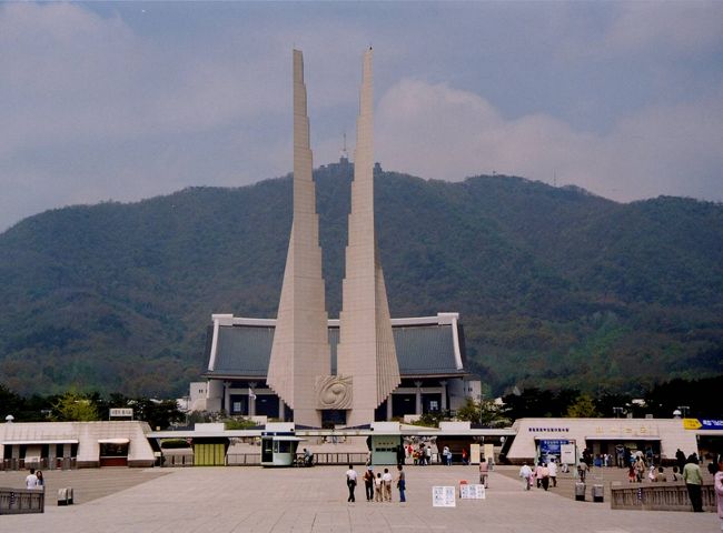 ＜2000年5月6日(土)＞<br /><br />　旅もいよいよ終盤になってきました。今日からは、釜山へ向かってひたすら南下の行程です。<br />　　　<br />＜チョナン(天安)の街＞<br />　チョナン(天安)は、今回初めて訪れました。この地を経由するのは､郊外の独立記念館見学が今回の目的地の一つだったからです。テグーに向かう途中で、立ち寄る計画にしていました。<br />　ソクチョからチョナンへは市外バスで移動しました。一人当たり5400ウォンでした。山間を通るバスは､新緑だけが印象に残りました。　<br /><br />＜独立記念館＞<br />　バス料金は、一人当たり600ウォンでしたから､さほどの距離ではないと思っていました。しかし、大間違いでした。たっぷり1時間半ほどかかりました。途中､市内、郊外ともに多少の渋滞はありましたが､大変にお値打ちなバス料金です。<br />　名古屋で､M鉄道のバスに乗れば､間違いなく千円以上は請求されそうな距離です。大雑把に韓国の物価は日本の二分の一、公共交通機関は五分の一と考えていましたが､その基準からは大分乖離しました。日本の場合、1時間半を300円のバス代では､人件費どころか､ガソリン代も出ないでしょ。帰りは別のルートで1時間40分以上かかり、やはり料金は一緒でした。<br />　余りバス代が安かったので､本題に入るのが遅れました。独立記念館は､壮大な規模で建設された民族教育の場所でした。日本人として､少し居心地が悪く感じる点も多かったのは事実です。韓国における反日教育に因んだ記念館とも聞きました。それにしても、壮大な記念館です。ソウルの戦争記念館でも感じましたが､この種の事柄にかける韓国のパワーには恐れ入ります。<br />　世界の常識で言えば､日本の方が異常なのかも知れません。戦後の長い平和は素晴らしいですが､その結果としての平和ボケは極めて憂慮すべき事でしょう。そんな思いを抱きながら訪れた記念館でした。<br />　独立博物館は､歴史博物館でもありました。ただし､現在の民族独立に関しての力点が殊に勝っていました。そのコンセプトの元にレイアウトされていると考えられました。<br /><br />＜チョナンからテグーへ＞<br />　チョナンからテグーまでは鉄道で移動しました。ソウルからでは手に入らなかったかも知れませんが､チョナンからテグーまでのセマウル号の切符が手に入りました。これで、行程的にも少し楽になりました。実は､セマウル号に乗るのは、今回がはじめてです。<br />　2時間ほどかかりますから､名古屋・東京間の距離程度でしょう。一人当たり、19700ウォンですから､日本の五分の一程度の料金です。在来線を含めて､韓国の鉄道は安い料金です。<br />　セマウルの乗り心地は申し分ありませんでした。途中1箇所だけ停まり､予定時間にトンテグー(東大邸)に到着しました。テグーの新幹線駅はトンテグーです。チョナンからテグーまでの新幹線ルートは韓半島を斜めに半分ほどを南下します。<br />　途中､丘陵地が多いはずですが､トンネルの数はさほど多くありませんでした。山陽新幹線に比べれば､格段に少ないように感じました。その分､新緑の景色を楽しむ事ができました。<br /><br />＜テグー(大邸)の街＞<br />　テグーの街は､5、6年程前に一度訪れる計画でした。しかし、丁度その時、地下鉄工事中のガス爆発事故が起こったばかりなので､やむなくコース変更した記憶があります。その地下鉄も大分完成しました。一部未完成の箇所もありましたが、6号線までが案内表示にありました。<br />　テグーは韓国有数の大都市です。ソウル､釜山には及ばないものの、5本指には確実に入るようです。釜山などと同じように、広域市に指定されています。セマウル号でソウルから南へ約3時間、釜山までは約１時間の距離です。交通の要所でもあります。<br />　翌朝少し早く起きて、ホテル付近を散歩しました。街路樹にヒマラヤ杉を使ったところもあり、十分に広いメイン道路でした。これは､韓国各地で経験した事ですが､今は、街の清掃が行き届いています。10年以上前の記憶では､街のゴミなどには余り関心が払われていなかったようです。どちらかと言えば､誇りっぽく､ゴミがあちこちに散らかっている印象を強く持っていました。<br />　断片的な記憶では『山に木を植える運動』『街に花一杯運動』等がキャンペーンされていて､今回は『ゴミを出さない､ゴミを拾おう運動」の類が展開されているのかも知れません。しかし、これは全くの推測です。<br />　ところが､ソラクサンではバス待ちのご年配の方がゴミ拾いをされたり、ウルルンドでも清掃のグループを見かけたりしましたので、強ち外れていないような気もします。ゴミ箱が分別収集に換わっているところも多く見かけました。これは､ISOの関係があるのでしょうか？元々、韓民族は白色を大切にする、清潔好きな民族なのかも知れません。<br />　テグーでの宿は、1階に生簀のある料理店が入ったビルの一角でした。まだ新しい建物でした。インチョンでの宿の例があるので､何軒か下見して、慎重に吟味して決めました。<br /><br />＜バス案内システム＞<br />　ウロクドンへの交通手段が分かりませんでしたから、今晩中に見当をつけておくことにしました。ウロクドンへのバス経路は､テグーの街中にバス案内システムがありましたので､これを利用しました。<br />　日本での『あいうえお』に相当する、ハングルでの『カナダラマ』で検索しました。路線名が分かっていれば、こちらでも検索できます。目的の路線番号を選択できたら、経路シミュレーションができます。地図ベースの上に､停留所名が次々と表示されて行きます。ハングルを相当読み慣れていないと､そのスピードには、付いていけません。<br />　ウロクドンへの経路も、路線番号の見当が付きましたので、シミュレーションしました。しかし、幾度シミュレーションしてみても、確実な事は分かりませんでした。最後の目的地方面で、目的地と反対方向の東に曲がってしまったからです。それで、判断に困りました。その時、携帯を持った40前後の男性の方が顔を出して、一緒に検索を手伝ってくれました。<br />　しかし、検索結果は､芳しくありませんでした。<br /><br />　｢この地下鉄駅付近からは、ウロクドン行きのバスは出ていません｣<br /><br />　｢地図の下の方が切れているので､最後までは分からない｣<br /><br />　と、教えてくれました。それで､地下鉄駅を移動してバス停を探してみましたが、目的は達せられませんでした。<br />　結局､『元の地下鉄に戻って、もう一度検索システムで探そう』と言うことになりました。今度は少し事情が読めてきましたので､『目的のバス路線がどこで地下鉄路線と交差するか』だけに的を絞って、繰り返しシミュレーションしました。その地下鉄駅の見当が付きましたので、明日､その駅で降りてバスを待つ事に決めました。<br />　その地下鉄駅は『半月堂』でした。宿を取った西部市外バスターミナルから最寄の『聖堂池』駅から7つ目の駅です。その事を頭に刻み込みました。テグー駅からは2つ手前の駅です。<br />　それにしても、簡単な屋根がついた屋外に、マッピングシステムを使ったシステムが、誰でも自由に使えるよう設置してあったのには感心しました。階層式の検索システムで､使い勝手に問題はありません。しかし、更に英語､日本語の副音声などがついていれば申し分ありません。しかし､これはまだ贅沢かも知れません。<br /><br />＜小さな焼肉店＞<br />　夕食は焼肉の店を探しました。立派な店もありましたが､鳥と豚を扱っているお値打ちそうな店が見つかりましたので､こちらに入りました。豚肉はかなり好い部位を使っているようです。なかなかの味でした。<br />　胡麻の葉とサニーレタスは、無くなるとすぐに追加してくれました。気が利いた、まだ若い店主に好印象を持ちました。料金も壁に書いた値段通りでした。日本でいえば､公共領収証のような紙を渡してくれました。領収書は、締めて3万6千ウォンでした。<br />　ビールと､焼酎をそれぞれ2本とって､一人当たり1200円でした。ビール、焼酎も１本2500ウォンと記載されていました。またテグーに来る機会がありましたら、立ち寄ってみようと、翌朝の散歩の時に、店の写真を撮っておきました。泊まった宿から、すぐ近くの所です。<br /><br /><br />　　仁川から天安に向かう途中にて　<br />　韓の春眼に馴染たる山路行く<br /><br />　若緑窓に流れて韓下る<br /><br />　韓南下テグーの春は今盛り<br /><br />　　独立記念館へ向かう途中にて<br />　席譲り譲られ韓の春を行く<br /><br />　髪染むる子も席譲る春の旅<br /><br />　街路樹の若葉替りぬ遠き道<br /><br />　かの國に日本の苦き春想う<br /><br />　　独立記念館にて<br />　憤の國胸に重たし八重躑躅<br /><br />　民族の歴史重ねて韓の春<br /><br />　海棠や花萎れつつ石畳<br /><br />　　テグーの宿にて<br />　宿の旗春風揺り一日終ゆ<br /><br />　春の風通して旅の衣干