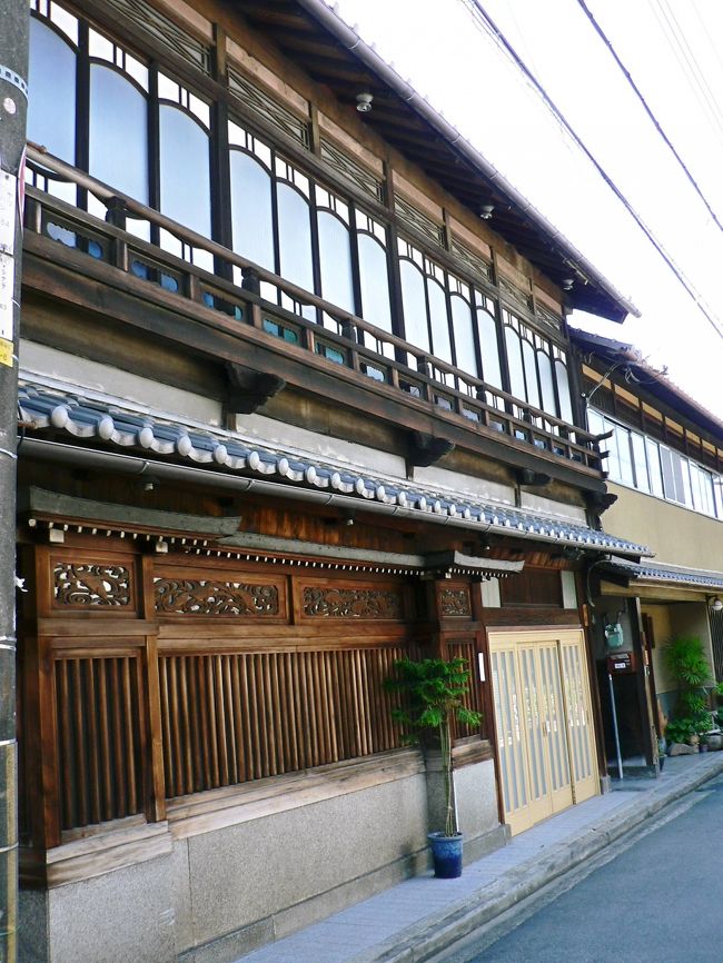 「橋本」は行基(ぎょうき668−749年)が725年に架けたと言われる「山崎の橋」のたもとにあるのが地名の由来で紀貫之(866−945年)の「土佐日記」にも登場する。「橋本」は京街道の宿場町であり、宿泊客の多くは男山・石清水八幡宮に参拝する人達だった。「山崎の橋」は何度も流され、文禄年間(1592−1595年)の架橋後は1930年に八幡の桂川・宇治川・木津川の三川合流点に、御幸橋(木津川御幸橋352m、淀川御幸橋262m)が架設されるまでは、対岸の山崎とは「山崎の渡し」と呼ばれる渡し船で往来していた。「山崎の渡し」は1962年まで運行しており、谷崎潤一郎(たにざきじゅんいちろう1886−1965年)は『蘆刈』(1932年)で「男山はあたかもその絵にあるやうにまんまるな月を背中にして全山の木々の繁みがびろうどのやうな津やをふくみ---」と山崎の渡し舟からみる男山の光景を描いている。<br />「橋本遊郭」は男山・石清水八幡宮とともに栄えた。源義朝(みなもとのよしとも1123−1160年)の妾の一人は橋本から出たと言われるので、1000年も昔から遊里があったのだろう。井原西鶴(いはらさいかく1642−1693年)の『好色一代男』に描かれ、淀川三十石舟舟歌にも歌われており、江戸時代中期以降は全国的に有名な遊里だったようだ。1872年に京都府から正式に遊郭と認定され、最盛期には、京街道沿いに石原楼、京華楼、いろはなど75の妓楼が並び娼妓は400名以上だったとのこと。最盛期の「橋本遊郭」は宮尾 登美子(みやお とみこ1926年−)原作の1982年の映画『鬼龍院花子の生涯』にも登場している。1958年の公娼制度廃止後、遊郭の灯は消え現在は閑静な街になっているが民家の屋根、玄関、格子の造りには遊郭の華やかな面影が残っている。<br />(写真は橋本遊郭の華やかさを残す民家)<br />