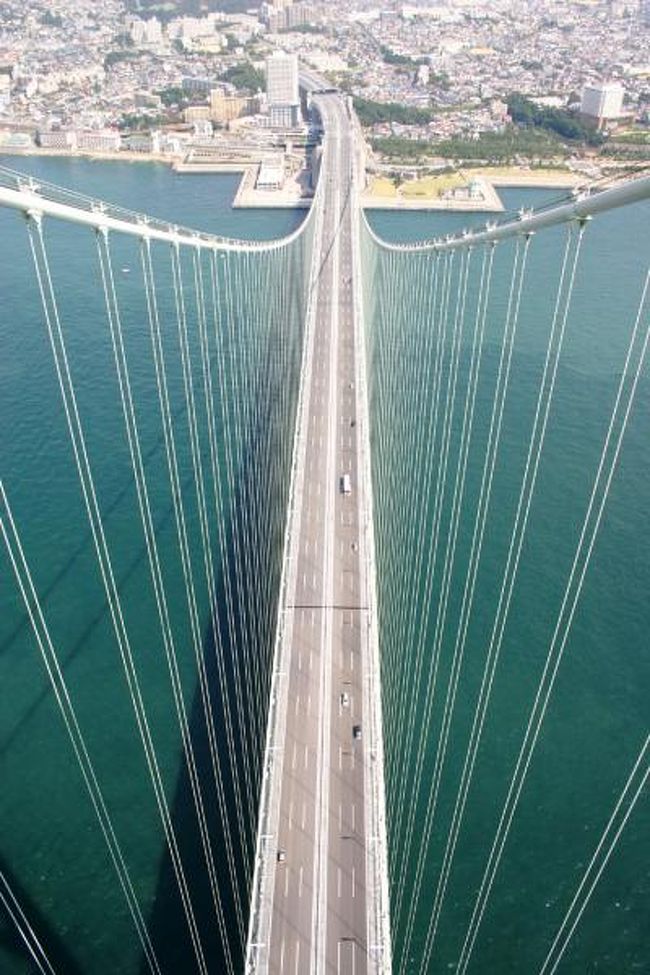 世界最長の吊橋・明石海峡大橋の塔頂に登ってきました。<br />このツアーは、4月から11月の間、<br />午前と午後の部の2回実施されており、事前申し込みが必要です。<br />午前・午後ともに定員が30名ということで、<br />定員になり次第、締め切られるということです。<br />私は、旦那様と会社の同僚と全4人で参加しました。<br />午前の部に参加したのですが、朝9：30分に受付開始、（遅れると参加できないようです）<br />9：45分からツアーは始まりました。<br />最初は、教室のようなお部屋で明石海峡大橋の歴史や<br />できるまでの過程などを聞きました。<br />その後、敷地内に併設されている「橋の科学館」で<br />これまた明石海峡大橋の仕組みや使われている材料などを学習しました。<br />そして、教室で渡されたヘルメットとベストを着用し、<br />手荷物などは全てベストのポケットに収容して両手を空いた状態にし、イヤホンマイクを装着していよいよ橋の頂に登る時間がスタートしました。<br /><br />参加者30名はだいたい10名づつの3つの班に分けられています。<br />明石海峡大橋を知り尽くしたツアー・リーダーがグループをエスコートしてくれます。このツアー・リーダーはおじさんでした。<br /><br />明石側から一番目にある塔の上に行くそうですが、それでも1Km以上歩いてそこまで向かいます。<br />その歩くのが、普段私たちが車を走らせている下に作られているメッシュ状の通路。<br />海抜60mくらいのところに作られているのですが、<br />メッシュ状ということで、歩いている真下には広大な海が広がっており、<br />あまり高さに対する恐怖感は無い方だったのですが、<br />初めて足がすくむっていうことを感じたような気がします。<br />この歩道は最後まで慣れませんでした。<br />通路を1km以上歩いた後、最初の橋げたのところに到着し、<br />そのコンクリートで作られた所には頂上まで行くエレベーターが設置されており、それで頂上まで上がっていきました。<br />本来は、掃除や点検用に設置されたエレベーターのようです。<br />橋にエレベーターがあるなんて知らなかったもので驚愕でした！！<br />そして、頂上に到着〜〜♪<br />普段は見ることはできないであろう見事な景色を堪能して大満足でした。<br />海抜300mってもっと寒いと思っていたのですが、思いのほか暖かく、風も少なく快適空間でした。<br />頂上には、コンクリートの壁がきちんと作られており、恐怖感はありませんでした。<br />ここへたどり着くまでの道のりの方がはるかに怖かった・・・<br />参加費は、最後に認定書と、上で撮ってくれた記念写真、<br />施設内の喫茶店で飲めるジュース券がついて2100円でした。<br />（2009年現在は、ジュースなしで3000円になっているようです）<br /><br />明石海峡大橋ブリッジワールド体験ツアー　http://www.jb-honshi.co.jp/bridgeworld/index.html<br /><br />