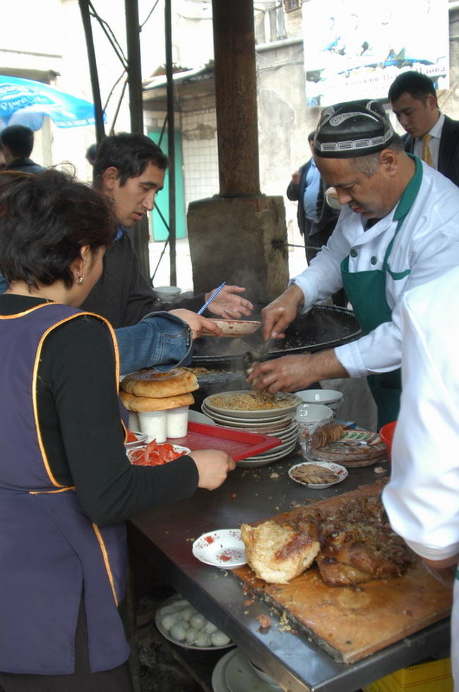 中央アジアのどの町でも食べられるプロフ、日本流で言えばピラフ、チャーハンは炒めるがプロフはお米から煮たご飯料理である。タシケントにはプロフセンターというプロフ専門のお店がワールドトレードセンターの近くにあり、ランチに食べに行った。<br /><br />このプロフセンター、ウズベキスタン料理屋が並ぶ一角にありメニューはプロフだけの専門店。作り方は大きな鍋に肉（ビーフorラム）の塊、お米、香辛料などを大きな鍋にいれ炊き込む。これがたいへん美味。<br /><br />通訳と一緒に行ったのだが、プロフとっしょにリピョーシュカ（釜で焼くパン）、サラダを注文した。大きな皿に盛るばあいと個別に盛る場合があるようだ。プロフの上には一緒に煮込んだ肉の切り身（ビーフ）がのっている。ご飯とパンを一緒に食べるところがウズベキスタンらしい。それからグリーンティーを注文した。席は2階の全体がよく見えるテラス席、ウエイトレスや客の動きがよくみえた。テキパキとシステマチックに動くさまは感嘆に値する。隣近所の事務所からプロフだけを買いに来る客もいる。また、ウズベキスタン人だけではなくロシア系の客も目に付いた。<br /><br />遅いランチ時間に行ったがまだまだお客でいっぱい、５釜あるプロフはその日の終盤、残り少なかったがなんとかプロフにありつくことができた。<br /><br />プロフについて<br />http://www.orexca.com/cuisine_plov.shtml