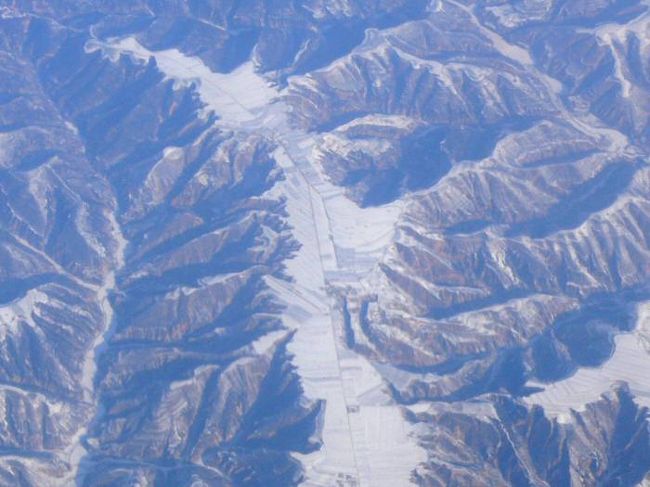 2月6日に昆明に飛行機で飛びましたが、うまい具合に<br />北京の長城と、山西省あたりの雪が降った黄土高原の<br />写真が飛行機の窓から撮れました。<br />右側の後ろの窓際の席を指定して、飛行機に乗った<br />成果です。<br /><br />この黄土高原の位置は飛行機のコースから考えて山西省か<br />陝西省のあたりと思われますが、位置が確定できない<br />ところが残念です。<br /><br />このあたりはあまり雪が降らないところではないかと<br />思いますが、中国の大雪の災害の後だったので、<br />雪が積もって白くなっていました。<br /><br />黄土高原の地形は黄土が暑く積もったところに深く亀裂が<br />入り、土地は縦に割れ黄土が荒々しく侵食されて行きます。<br />これをガリー地形というのだそうです。<br />空から見ると極めて特徴のある地形です。<br /><br />大地が削られていって、残った平らな上の<br />部分が、人の居住地帯であり、耕作可能な土地です。<br />人は土地が平らな高いところに住んでいます。<br />水などが少なく、痩せた土地ではないでしょうか。<br /><br />飛行機は一旦、北に向かって飛び立ったので、北京市の<br />北にある長城も見えました。<br /><br /><br /><br /><br />