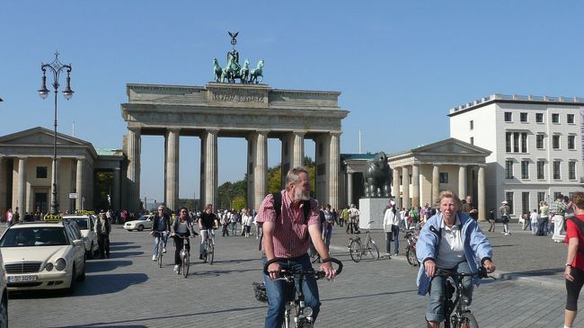 都城都市だったベルリンの18箇所あった都城の門のひとつで、フリードリヒ・ヴィルヘルム2世の命により1788年から3年間かけて建設。門の上には四頭立ての馬車（クアドリガ）に乗った勝利の女神ヴィクトリアの像を乗せた。<br /><br />ベルリンに遷都するまで、プロイセン王国の首都だったブランデンブルクに通ずる門としてこの名がついた。<br /><br />しかし完成直後にナポレオン・ボナパルトによりベルリンは征服されブランデンブルク門はナポレオンのパレードの舞台と化し、ヴィクトリア像はフランスへ戦利品として持ち去られた。<br /><br />その後のナポレオン戦争によりプロイセン軍がパリを占領すると、ヴィクトリア像は再度ベルリンに持ち帰られ、門の上に戻された。<br /><br />1868年に城壁が取り壊され、唯一残されたのがブランデンブルク門。<br /><br />「ベルリン壁」によりこの門は東ベルリンの行き止まりとなったが、1989年の「ベルリンの壁崩壊」により再び門の下を通ることが出来るようになった。<br /><br />今日も多くの観光客が色んな移動手段を使って、この門の下を往来していた。<br /><br />ところで門の前の犀の銅像は何なんだろう？<br />