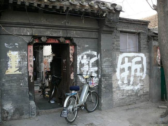 驢馬市大街の南側一帯は古くからの平屋が建て込んいて<br />そこは北京の胡同といわれる路地などがあり、昔ながらの<br />生活の風景が見えますが、実は「大雑院」とも言われている<br />ところで、スラム化しているような場所です。<br /><br />何故スラム化したかについては文化大革命などの<br />影響で、以前の住人を追い出して、その後を数人の<br />住人に分割したなどの歴史的経過があり、四合院の<br />中庭にも建物を作り、違法な（多分）建物を増設していき、<br />四合院の中は幅２mにも満たない通路だけが残されて<br />いる状態になっています。<br /><br />また中国人の性向として、囲いの中に家を作って住みたいと<br />いう気持ちがあるのかもしれません。<br /><br />「大雑院」の「院」には囲まれた場所と言うで、その<br />「院」には裏口などは決して無く、表の入り口だけを作り、<br />そこには門を設けるのが普通です、四合院もそういった<br />形式ですが、その四合院が歴史的な理由もあり、その中に<br />家族ではなく知らない隣人が雑居するようになったのが<br />「大雑院」です。<br /><br />昔からの四合院ではなくても、とにかく周りを囲った「院」の中に<br />住みたいらしく、囲った中にゴミゴミと密集して住みたいようです。<br /><br />実は「大雑院」の「雑」があらわしているように、「大雑院」の<br />中はは乱雑で、とても汚いのです。ここをみていると中国人の<br />住み方は汚いと言う結論を出したくなります。<br /><br />トイレは外の共同トイレですから、トイレも無く、台所も満足な<br />物は無いようです。そして狭く、乱雑に物が置かれています。<br />壊れた自転車や、拾ってきたレンガ等等・・・・<br /><br />観光用の胡同や四合院は汚くないですが、実は四合院と<br />言っても、洗濯物を乾す場所も無い、「大雑院」なのです。<br />では洗濯物はどこに乾すか？　人が通る狭い通路にパンツも<br />ぶら下げてあります。通り道も狭いですが住んでる場所も<br />狭いです。　二坪位の家もあります。<br /><br />「大雑院」の中は、観光で胡同巡りをする人などには<br />想像もできない世界があるのです。<br /><br />家といっても拾ってきたレンガでチョコチョコッと作ってしまった<br />ような家ですから、危険であるとも言えるのは確かです。<br /><br />それでこのような平屋が広がる一帯を危険家屋として<br />危険家屋造プロジェクトと云う名目で、立ち退かせ<br />取り壊す計画が北京ではあちこちで進んでいます。<br /><br />驢馬市大街の南側一帯もまた「危改」プロジェクトとして<br />取り壊しの計画が進んでいて、ここには潘家胡同などの<br />路地や、康有為（日本の明治維新を模範として清朝の<br />改革をすすめようとした人、しかし失敗した）の<br />旧居がありますが、全て取り壊されるようです。<br /><br />歴史的遺物があったとしてもスラム化していては残す<br />わけにはいかないのかもしれません。