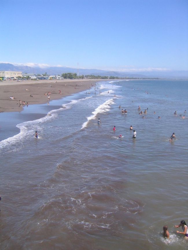 コスタリカの海の玄関口のプンタレナス (Puntarenas)<br /><br />そんなに 大きな街ではないけど、ビーチには 海水浴を楽しむ人で賑わっていた。ちょっとしたリゾート地のようだ。でも、今まで見てきた カリブ海の島々と違って 驚いたのが、茶色い砂!みんな泥だらけになってるし・・・。<br /><br />日本人のお客さんは こんな 汚そうな海には 入れないよ!なんて 言っていたけど、海の水は 実は綺麗なのかも?と思い、興味本位で 海に入ってみる。やっぱり 真っ黒、ドロドロになった(苦笑)<br /><br />ちなみに、プンタレナスは「砂の岬」という意味。5キロほども砂浜が海に とびだしたように続いていることから その名前がついたのだとか。<br /><br />とりあえず、腹ごしらえをしよう!と思い、ビーチのそばの露店をめぐる。道端では 何人も 同じようなサラダを売っている人いて、そのうちの1人の おばちゃんから サラダらしきものを購入。それが 安くて 旨い!!!おばちゃんに 何度も「おいしいよ!!!」と言ったら すごく 嬉しそうな顔をしてくれた。名前も 聞いたんだけど、忘れてしまった。後で、コスタリカ人の同僚 ジェイナに 説明したんだけど、名前はわからない、って。書き留めておけばよかった。悔やまれる。<br /><br />街の散策に出かける。小さな露店がいっぱい出ていて、アクセサリーなんかも すごく安い。お土産用のマグネットなんかも 他の場所より全然安い。熱帯気候のコスタリカにふさわしく、カラフルなものが多い。羽を拾うと幸せになるといわれている幻の鳥、ケツァルや、手押し車みたいなのが 有名なのか それをモチーフにしたものも多かった。<br /><br />それから、カフェのおじちゃんに頼んで、 アメリカドルとコスタリカの貨幣を 交換してもらった。いくらか よくわからないけど、カラフルなものと 真っ赤な紙幣、それから かわいい絵柄のコイン。これも 貴重なお土産。<br /><br />あたしが この露店めぐりを楽しんでいると、一人の男の人が からんでくる。最初は無視していたんだけど、しつこさに負け、結局、カタコトのスペイン語で 会話を続ける。ちょっと 酔っ払い気味のこのニカラグア人、ホセは バカンスで 遊びに来ているんだという。 なんだか 気がついたら あたしも ホセと意気投合。ホセはこの後、あたしの買い物にも 付き合ってくれて、あたしの名前入りネックレスを買って、プレゼントまでしてくれた。<br /><br />歩きつかれたので、ホセがお気に入りだという 近くのバーに立ち寄る。 地ビールを 飲んでいたんだけど、ホセは そのまま うたた寝をはじめてしまった・・・。普通寝るか?と思いつつも、ラテン民族だし、仕方ないか、と思うことにする。<br /><br />ホセが(寝てしまう前に)絵葉書を1枚買って、あたしに渡していた。「日本人の友達になんて なかなか 出会えるもんじゃない。この記念に、この絵ハガキを 僕のうちに 送ってくれ」って。なかなか かわいいこという人じゃないか。<br /><br />結局、その後 アメリカから送った 絵ハガキ。無事に ホセの家に届いたかな。
