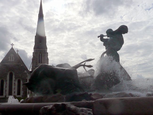 コペンハーゲン旅行といえば人魚姫の像、その近くのゲフィオンの泉も含まれるだろう。<br /><br />アマリエンボー宮殿前の水辺の散策が終わる頃、石造りの、童話に出てきそうな教会に出くわす。<br />聖アルバニ教会。<br /><br />続いて表れたゲフィオンの泉は教会の雰囲気にピッタッリ。<br /><br />泉を一回りして写真に納める。<br />後向きだが、逆光のゲフィオンの泉も教会に似合う、幻想っぽい写真と成った。<br /><br />　<br />勝利の女神像の高い搭の建つ花畑を過ぎると、ややカーブした石積みの波打ち際に人魚姫の像のはあった。<br /><br />スカンジナビア旅行ブログの表紙は、スカンジナビアの象徴として、この人魚姫の像をあしらった壁紙を使った。<br />(この壁紙はMicrosoftのクリップアートから貰った人魚姫のイラストをホームページ用にアレンジしたもの。）<br /><br />18時15分、ここで初日の観光は全て終了し、バスは人魚姫の像を後にホテルへ。<br /><br />その途上バスはニューハウン、チボリ公園前等眺めながら通過したが、その際車上からのスナップは、翌日訪れるそれぞれの項でまとめて投稿します。<br /><br /><br />人魚姫の像への旅行マップ<br />http://www.geocities.jp/tshinyhp/hokuou/hokuoumap/copenhgen/ningyo/frameningyohime.html