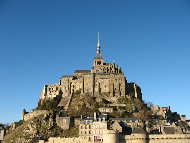 今回フランスに行くにあたって、パリと今現在どうしても外せないスポット、世界遺産でもある「モンサン・ミシェル」絶対に見ておきたい、当初ＴＧＶとバスで行こうかとも考えたが、バスの本数など制限があった為この部分だけ現地ツアーを選択しました、参加したエミツアーにはノルマンディーの田舎町のブブロン村にも寄り道すると言う、フランスの田舎の風景も見られると言うのでチョイス、早朝集合場所に行くと男性ガイドさんは日本人、好奇心をくすぐる人で色々話を聞いた、フランス在住２０年になると言う、日本の会社から３年パリに行かないかって話しがあって、パリが肌に合ったのか、そのまま日本の会社を辞めて現職にいたるそう、フランスにも大変な事はあるが、今の日本はもっと大変でしょうだって、道中はフランスの歴史や革命、戦争の事柄を詳しく話して頂き耳を傾けていました、僕の頭の中では片道３時間もあれば到着と思っていましたが、距離が３５０キロもあり片道５時間、東京から名古屋、九州なら博多から鹿児島位の距離、それだけの距離を日帰りで観光するのですから。前日の雪に変わって当日は非常に良い天気に恵まれて青空とモンサンミシェルを自分の目とカメラで捉える事が出来ました