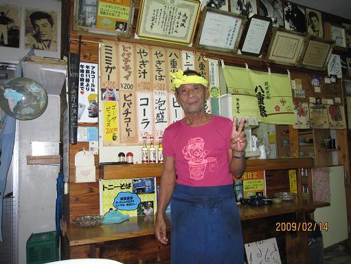 沖縄には琉球王朝以来の伝統料理、王宮料理など外来者を楽しませてくれる料理が盛り沢山あるが、石垣最後の夜、数日前から心に期していた「ひーじゃー」、「山羊肉の煮込み汁」を食べに出かけた。<br /><br />沖縄本島でも「ひーじゃー」を出す店はそれ程多くなく、浦添に１軒あって時折食べに行ったこともあったが、ホテルで聞いたところ、この石垣でも市内には２-３軒しかないようだ。<br /><br />その内の一つ、一昨日通りすがりに目にした「トニー食堂」へ行って見る。<br /><br />店の外も中もまあ、賑やかなこと。トニーと言うから「トニー・カーチス」のファンかと思ったら、若くして亡くなった「赤木圭一郎」のファンで、と言っても今の若い人には「赤木」も「カーチス」も殆ど知らないと思うが、その「赤木」の写真、プロマイドで店内は隙間もなく飾られている。<br /><br />ふと見るとその横に石垣市教育委員長からの表彰状も掲げられていて、更にその書かれている内容を見ると、「通事国浩殿」となているではないか！<br /><br />ああ、この人、この店のマスターが「通事」さんだったのか！<br /><br />もう何年も前、司馬遼太郎氏の「街道を往く」を読み漁り、日本各地の風物に触れ、旅に出なくても旅行した気分になり、夢の中で旅もし、後日、機会があってその土地を訪ねたりもしたが、その司馬さんもこの石垣までやってきて「街道を往く」を書いている。<br /><br />その中で確か「通事」氏のことも書かれていて、この店のことも出ていたように記憶していた。<br /><br />そこでマスターの「通事」さんに司馬さんのこと、街道のこと、珍しい姓のこと、等を聞いてみたが、全く思い当たらない風だった。<br /><br />大体司馬遼太郎という作家名すら心当たりがなく、話していて当方が拍子抜けしたが、今年７３歳になるというご本人は至って快活で、話し好きで、店内に英語の書き込みなどが掲示されていても、ご本人は英語は全く分らず、当方内心これでは「通事姓」が泣くなあ、との心を見透かせてか、自分の息子は今５０になるが、その息子とか孫は英語がペラペラだとか、矢張りどこか「姓」へのこだわりを棄てきれず、当方、出された「ひーじゃー」（ヤギ汁）の湯気を吹き吹き、快活な沖縄人の話しに聞き入った。<br /><br />本島の「ひーじゃー」は汁の中にヨモギ（ふーちばー）とか生姜（うこん）が沢山入っていて、ピリっとした味もあったが、石垣のそれは、それ等具材が少なく、本島のよりはやや劣った味付けであったが、それでも数年ぶりに食べた山羊汁。<br /><br />王宮料理の奥ゆかしさも良いが、こうした庶民の味、庶民が１年に一度か二三度食べる山羊汁を元気な石垣の古老からの話を聞きながら食べることが出来、その味以上の満足感が得られたものだった。<br /><br />４日間の旅を終え、明日はいよいよ石垣を離れる。その最後の夜に「街道を往く」にも出てきた現実の「通事」さん（本人が知らないことが奇妙ではあるが）と話ができたことでも、今回の旅行は価値あるものだった。