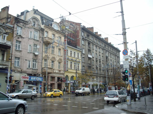 2007年10月20日<br /><br />ブルガリアの首都ソフィアは、寂しくて、どこか物悲しい街である。<br /><br />街で一番の大通りには、たくさんの人が歩いていたが、皆、寒そうに下を向きながら歩いていた。<br /><br />どの建物にも華やかさはなく、たぶん旧共産党時代の名残が、いまだに漂っていた。<br /><br />街の中心には荘厳で巨大な建物があり、その近くには、同じく巨大なキリスト教の寺院があったが<br />それらを取り巻くようにあった黄色い広場が冷たい時代の何かを物語っているように思われた。<br /><br />私は、この日、昼食のために、あるレストランを探していた。<br /><br />それは街の中心から少し歩いた、若者が集まる（と言われている）繁華街の中にあるはずだった。<br /><br />しかし、その辺りの道は複雑で、また始め私は地図の見方を間違えてしまっていたので<br />簡単には見つけることができなかった。<br /><br />私は２時間ほど、街のある一角をウロウロし続けていた。<br /><br />ブルガリア人の若者たちが、ほどほど歩いていた。しかし皆、本当に寒そうで、ほとんど誰も<br />この日本から来た旅人の存在に気づかなかった。彼らは下を向きながら歩いていたからである。<br /><br />私はお腹が空いてきたので、レストラン探しを中断して、途中でピザを一切れ食べることにした。<br /><br />１Lv（＝約85円）の割には大きくて、日本で普通に売ってそうな大きさの３倍はあった。<br /><br />街の隅っこで、ひっそりと隠れるようにあったピザの小さなファースト・フード店。<br /><br />店員はおばちゃん一人で、まったくの個人経営に見えた。<br /><br />しかし恐らく、その近辺ではまぁまぁ有名だったのか、ブルガリアの若者達が、私の後に<br />ぞくぞくと店に入ってきて、ピザを片手に寒空の下に出て行った。<br /><br />ブルガリア料理は煮込み系が多くて、チーズをふんだんに使った濃厚な味が得意なせいか<br />ピザもなかなか得意のようである。<br /><br />小腹を満たしてしまった私は、この後どうしようか・・・？と考えなくてはならなくなった。<br /><br />ぶ厚い曇り空の下で、外はかなり冷え込んでいて、少し雨が降っていた。<br /><br />ソフィアの街の観光は昨日の時点でほぼ終わっていた。<br /><br />というのも、見るべきところは、旧共産党本部近くに集中してある教会と博物館ぐらいしかない。<br /><br />そして私は明日には移動して、別の街に行くつもりだった。<br /><br />私は、てきとうなカフェにでも入って本でも読んで、時間をつぶそうと思った。<br /><br />近くには２軒のおしゃれなカフェがあり、私はそのうちの１軒に入った。<br /><br />何も期待せずに。ただ寒さをしのぐ為に、また、読書の為だけに。。。<br /><br />・・・<br /><br /><br />店内はほど良く暖まっていた。<br /><br />ブルガリアにしては少し高級？なカフェで、カプチーノが１杯３Lv　ほどだった。<br />しかし、リラックスできそうな一人用のソファがいくつかあり、読書をするには最適そうに見えた。<br /><br />店員からカプチーノを受け取ると私は、空いてそうな席を探した。<br />いくつかの席には「Reservation」という札がテーブルに置かれていた。<br /><br />私は、柔らかそうなソファに座りたいと思ったが、予約なしのソファの相席は２つしかなく、<br />ひとつはすでに男性がひとりで座っていた。<br />もうひとつは空いていたが、黒革のジャケットが置かれていた。そこは誰も座っていなかったが、しかし<br /><br />誰かの洋服だけがあった。そして、その隣りには、サングラスをかけた男が一人でタバコを吸っていた。<br /><br />私は、その男に、「この席は空いてるか？」と英語で聞いた。<br /><br />すると彼は一瞬ビックリして、慌ててそのジャケットを掴み、口をパクパクさせた。<br /><br />何を言ったか分からなかったが、どうやらジャケットは彼の物で、席は空いてるみたいだった。<br /><br />たぶん彼は、いきなり英語で話しかけられたので、英語で返事をするのに戸惑ったようだ。<br /><br />私はそこで「いや、いいんです。ジャケットはそのままでも。私はこっちに座りたいだけなので・・・」と言った。<br /><br />彼はホッとしたようで、納得したが、ジャケットを持ち上げて、着ようとしたが、再び席に置いて笑った。<br /><br />私も笑って、席に着いた。<br /><br />そしてカバンの中から本を取り出して、読むことにした。<br /><br />けれども数分で、何か、なんとなく読書に集中できないことに気付いた。<br /><br />私は本から顔を上げて店内を少し観察した。<br /><br />店内はアフリカっぽい雰囲気で、どこか民族音楽のようなメロディが流れていた。<br />オレンジ色の壁にアフリカの大地の絵が描かれた布が貼ってあった。<br /><br />しかし、なぜか？店の名前は「Onda」と書かれていた。オンダ？　日本人の名前みたいだなと思った。<br /><br />というわけで、色々な意味で、そこのカフェはブルガリアらしくなかった。<br /><br />店のメニューは英語で書かれていたが、店員は私の英語を理解しなかった。<br /><br />しかし、店員の女の子たちは雑談をしながら楽しそうに働いていた。<br /><br />外のソフィアの街中とは対照的に、店内は明るく温かい雰囲気に包まれていた。<br /><br />店内の観察を一通り終えると、隣りの席にいたさっきの男が話しかけてきた。<br /><br />「どこから君は来たんだ？」　<br />（Where are you from？　以下すべて本当の会話は英語）<br /><br />日本。と私は答えた。　<br /><br />彼は納得したように、ニヤリとして、すぐに続けてこう言った。<br /><br />「このタバコはうまいよ」<br /><br /><br />