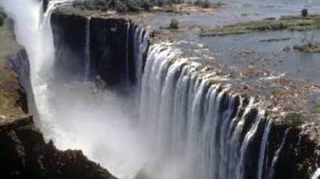 アフリカ南部、ザンビア南端リビングストン又はジンバブエのビクトリアフォールズからすぐ近くの国境を流れるザンベジ川に位置する滝。地表に出来た巨大なひび割れに、ザンベジ川の豊かな流れが一気に滑り落ちるという感じである。 非常に水量が豊富で、高さ１２０ｍ幅１７００ｍ 水煙は、遠くまで雨のように降り注ぎ、虹をつくりながら５００ｍの上空まで雲のように舞い上がる様子は壮観である。<br /><br />