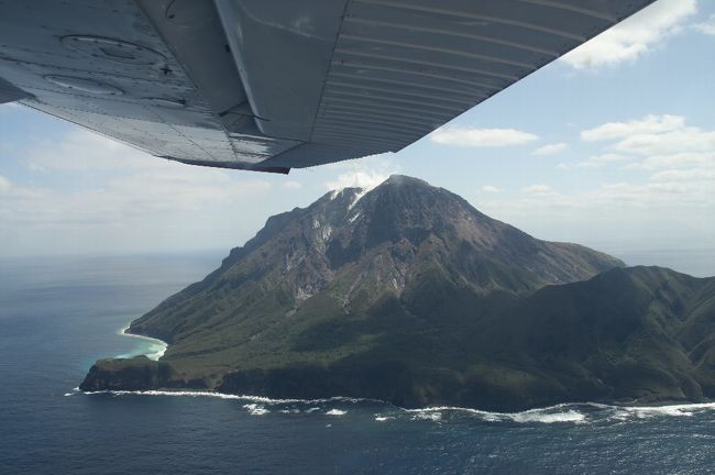 大学の先輩のMさんが飛行機をチャーターして薩摩硫黄島へ日帰りで飛ぶのに同行者を募集していると言う。<br />家人に聞くと、意外にも「行きたい」というので同行することにする。<br />もともと14日に飛ぶ予定だったが、天気が悪いので直前になって15日に変更した。<br />鹿児島には予定の変更が効くように14日入りしていた。<br /><br />霧島に雪もちらついた14日とは打って変わって、15日の鹿児島は雲なしの快晴だった。<br />鹿児島市内のホテルからレンタカーにて集合場所の鹿児島空港へ向かう。<br />鹿児島空港では9:30に待ち合わせ。<br />予定通り、Mさんと落ち合い、新日本航空の方の車で空港南にある本社事務所まで行く。<br />事務所では社長さん直々にご挨拶いただき、手続きなどをする。<br />とはいえ、何かの書類にサインして、お金を払うだけだが。<br />鹿児島?硫黄島のチャーター代は136,500円。高いと言えば高いが、そうそうない機会と考えると出してもいいかなと思える値段。もともとMさんは1人でも行く予定だったので、こちらは2人併せて半額分で許してもらう。。<br />コーヒーをごちそうになり落ち着いてから、いよいよ出発。<br /><br />事務所前すぐに格納庫があり、その前にはすでに飛行機が待機していた。<br />飛行機はセスナ172というものでパイロットを含めて4人乗り。従って満席。<br />パイロットとMさんが前席に乗り、我々2人が後ろに乗る。<br />10時に出発。管制と交信しながら滑走路に向かう。<br />すぐ前に出発する通常の飛行機と比べると心細くなるほどのこぢんまりしている。<br />すんなりと離陸し、枕崎方面に針路をとって進む。枕崎まで30分、そこから海上を30分進むと硫黄島に着く。隣にある竹島・黒島を見て、島の東側からぐるっと島の南側へ回る。島の東には大きな火山があり噴煙をあげているので迫力がある。<br />島の南側から滑走路に着陸する。小さい島で、風の影響とかあるのだろう、なかなか着陸が難しい島だと行っていた。ベテランのパイロットさんで、何の問題もなく無事着陸。<br />飛行場は通常は開いていないが、使用する時は役場の方に事前に連絡して開けておいてもらう。<br /><br />島では、事前にいろいろ問い合わせなどしていたからか、役場の方が待っていてくださった。車で島を案内してくださると言う。<br />まずは島の南端の永良部崎に向かう途中の「岬橋」へ。ここからは集落が一望できる。海は鉄分を含む温泉が湧き出しているため、赤くなっているとのこと。<br />集落を通り過ぎて、硫黄岳の南の麓にある東温泉へ。波打ち際近くに湯船がある。3つの湯船にお湯を順に流し入れることで適温になるようにしている。<br />時間はあまりないが足だけ使ってみる。ここは珍しいミョウバン温泉で澄んだ緑色をしている。口にしてみるとサイダーのような酸っぱい感じの味がする。<br />今度は島の北側の平家城あたりまで行く。硫黄岳を北側から眺める。次は同じく島の北側の坂本温泉へ行く。こちらの方に地元の人がよく来ると行っていたが、たまたまなのかお湯が少なそうであまりちゃんと入れない気がした。<br />そろそろ空港へ戻る。道すがらクジャクが歩き回っていた。昔誰かが持ち込んでそのまま野生化したらしい。<br />結局1時間半ほど滞在して、鹿児島へ戻る。<br /><br />帰りはまっすぐ鹿児島空港に戻る。帰りも1時間かかる。14時頃、無事に鹿児島空港到着して終了。<br /><br /><br />