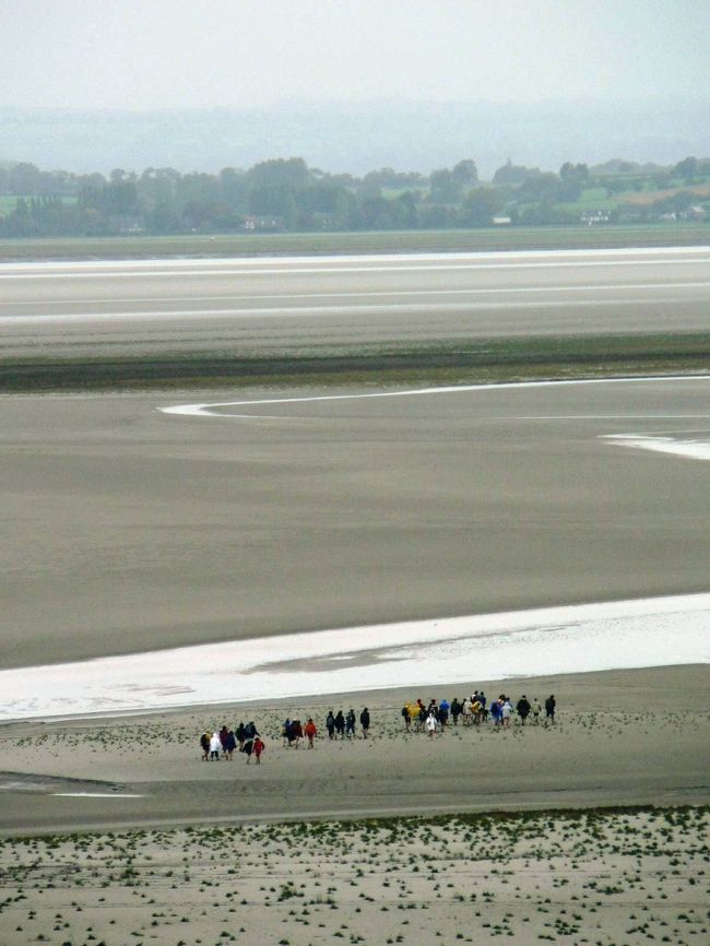 モン・サン・ミッシェルは砂浜に囲まれた島に築かれた修道院を見る夢が実現した。修道院は966年から建設され、その後何度も増改築されているそうだが離れ小島に良くこんな大きな修道院を建てたものだと思った。<br />モン・サン・ミッシェルは残念ながら雨が降り続きゆっくり光景を楽しむ気分になれなかったうえに濡れたデジカメが途中から動かなくなった。デジカメは乾いたら自然に治ったのだが残念なことにモン・サン・ミッシェルの写真はほとんど撮れていなかった。バスでレンヌ駅に戻り、駅周辺を歩いて列車でパリ・モンパルナス駅に出て、パリの凱旋門やモンマルトルの夜景を楽しんだ。凱旋門の上からパリの放射線状の道と街並みを見ることは1971年にやり残した観光だったし、モンマルトルのサクレ・クール聖堂の夜景は1971年に見て、近くから見てみたいと35年も思っていたことだった。<br /><br />関連旅行記−欧州・バックパッカーの旅【21】 フランスのモン・サン・ミッシェルとパリの夜景:http://4travel.jp/traveler/sasuraiojisan/album/10111845/<br />(写真はモン・サン・ミッシェルの砂浜を歩いて渡る人達)<br /><br />