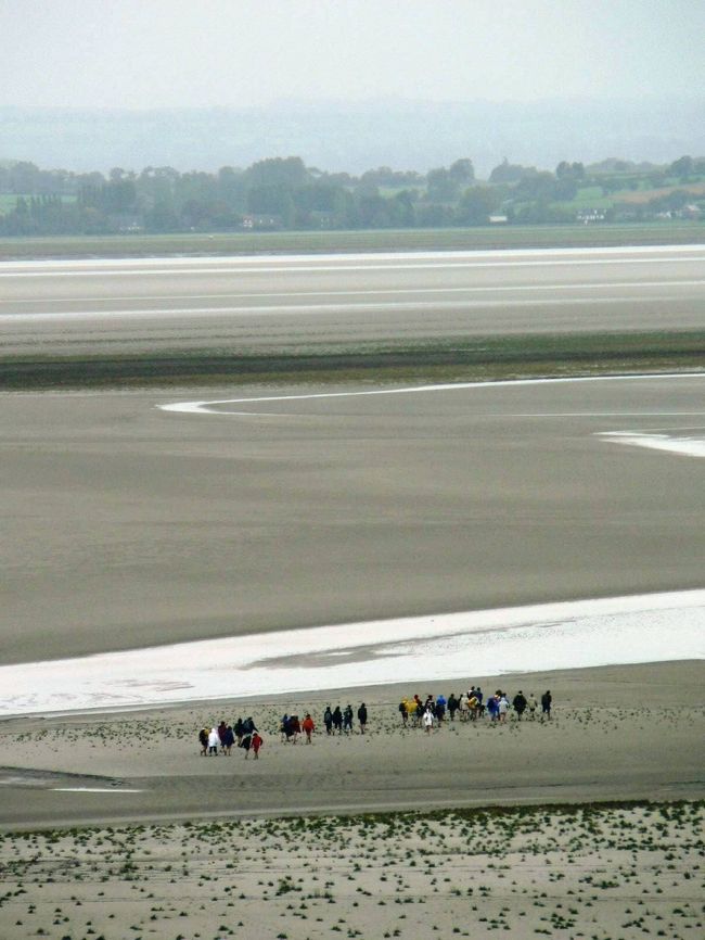 モン・サン･ミッシェルは砂浜に囲まれた島に築かれた修道院を見る夢が実現した。修道院は９６６年から建設され、その後何度も増改築されているそうだが離れ小島に良くこんな大きな修道院を建てたものだと思った。<br />モン・サン･ミッシェルは残念ながら雨が降り続きゆっくり光景を楽しむ気分になれなかったうえに濡れたデジカメが途中から動かなくなった。デジカメは乾いたら自然に治ったのだが残念なことにモン・サン･ミッシェルの写真はほとんど撮れていなかった。バスでレンヌ駅に戻り、駅周辺を歩いて列車でパリ・モンパルナス駅に出て、パリの凱旋門やモンマルトルの夜景を楽しんだ。凱旋門の上からパリの放射線状の道と街並みを見ることは１９７１年にやり残した観光だったし、モンマルトルのサクレ・クール聖堂の夜景は１９７１年に見て、近くから見てみたいと３５年も思っていたことだった。<br /><br />関連旅行記−欧州・バックパッカーの旅【２１】　フランスのモン・サン･ミッシェルとパリの夜景：http://4travel.jp/traveler/sasuraiojisan/album/10111845/<br />（写真はモン・サン・ミッシェルの砂浜を歩いて渡る人達）<br /><br />