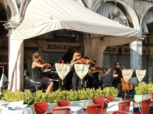 ヴェネツィアは音楽で溢れている。特に、サン・マルコ広場で朝から晩まで繰り広げられる生演奏は特筆ものである。ここに来た観光客は誰しも立ち止って生演奏に聞き入る。コーヒーを飲みながら若い女性ヴァイオリニストの演奏を身近で聴ける。こんな楽しい場所はない。さらに、ヴェネツィア市内では毎夜どこかの教会やホールで演奏会が行われている。よって、それらを探して聞きに行くのも楽しい。<br />写真：サン・マルコ広場「カフェ・クアードリ」の特設ステージで演奏する女性弦楽四重奏団<br /><br />私のホームページ『第二の人生を豊かに―ライター舟橋栄二のホームページ―』に旅行記多数あり。<br />http://www.e-funahashi.jp/<br /><br />