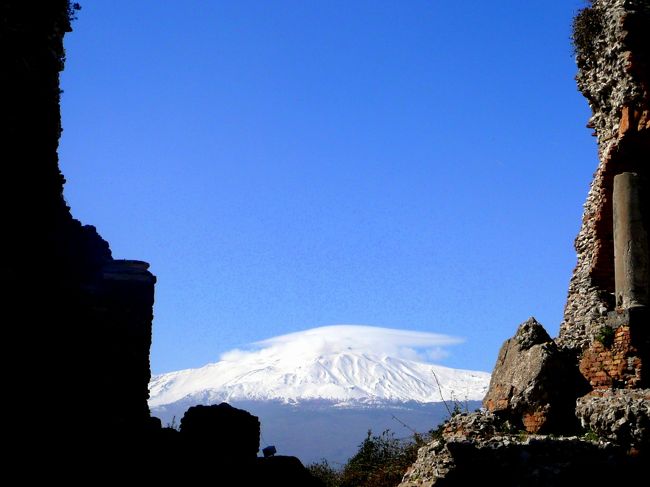 シチリア島＆南イタリア周遊旅情の旅は、ミラノ経由でシチリアのパレルモ空港に到着して始まった。<br /><br />シチリアはイタリアという長靴で地中海の中心に向かって蹴飛ばされ、北部はティレニア海、南部はイオニア海に囲まれて浮かぶ、ほぼ三角形の地中海最大の島。<br /><br />地中海の十字路といわれる要衝の地である上に、エトナ山から噴き出した火山灰が集積して出来た肥沃な地表を持ち、2万年も前から人類が生存していたらしい。<br /><br />この恵まれた島を人類は見過ごすはずは無い。<br /><br />地中海を中心とした、東西の歴史上の時代の勝者が次々とこの島の覇権を争った。<br /><br />歴史上シチリア島に明確な足跡を残したのは、西アジア（現レバノン辺り）からやって来たフェニキア人。<br />彼らは本来海洋通商民族で、通商の為の港を各地で建設したが、定住し街を建設することにはあまり興味は無かったらしい。<br /><br />組織的に定住がはじまったのは、紀元前8 世紀、島の南東部のシラクーサにギリシャ人が移り住んだことから始まるとされる。<br /><br />紀元前9世紀に北アフリカのカルタゴ（現チュニジア）を建設したフェニキア人との覇権争いに厭気を差したギリシャ人は、当時ほぼローマを統一した新興勢力ローマに援助を求め、争いの表舞台はローマ対カルタゴに移る。<br /><br />カルタゴの名将ハンニバルの奮戦及ばず、カルタゴがローマの手に堕ちるとローマはその手でギリシャも葬り、ここに初めてシチリア島全体の支配者が生まれることになる。<br /><br />しかし幸運なことに、そのローマもシチリアを単なる食料供給地としてのみ扱った為、シチリアでのギリシャの遺構が多く残され、今も我々の前に姿を見せる。<br /><br />西ローマ帝国滅亡後東ゴート族の侵略を受けたが、東ローマ帝国（ビザンチン帝国・首都は現トルコのイスタンブール）が奪還、東ローマ帝国は一時はシラクーサを首都とした。<br /><br />その際シチリアにモザイク芸術を中心としたビザンチン文化が持ち込まれる。<br /><br />次いでイスラム教徒のアラブ人がシチリア島を征服、パレルモにイスラム教国家の首府を置き、シチリアは最初の繁栄を迎える。<br /><br />時代が移り、11世紀に、当時パレルモを首府としていたイスラム教徒を襲い、シチリアの全土を手中に収め、シチリアの覇者となったのはナポリに侵攻していた、フランス北方の、ヴァイキングを祖とするノルマン人であった。<br /><br />彼らはそこにあった文化を吸収し、フランスの宮廷文化も取り込んだ、”ノルマン・シチリア”文化を創設した。<br /><br />12世紀には神聖ローマ帝国（ドイツ・ホヘンシュタイン家）の支配下にはいったが、この両時代にパレルモは華を開き、世界から各層の人が集い、”世界の驚異”と称賛された。<br /><br />この繁栄に水を差したのが、皇帝派と教皇派との権力争い。<br /><br />教皇がフランスのアンジュー家から王を連れて来、これに反発していた亡命貴族が担ぎ出したイベリア半島のアンゴラ家・・ハプスブルグ家・・スペインブルボン家と支配者は移るが、一般市民には苦渋の時代が続き、これに反発する一団の中からマフィアの芽が育つこととなる。<br /><br />しかしこの目まぐるしい歴史のお陰でシチリア島は世界に類を見ない、東西文化が溶け合った遺産が数多く残された。<br /><br />我々のシチリアの旅は、パレルモを起点に、シチリアの歴史を遡るように、シチリア島を南下し、イオニア海沿いに東へ進み、シチリア発祥の地シラクーサを経て、シチリア島の玄関口メッシーナ海峡からイタリア本土に渡った。<br /><br /><br /><br />ssiシチリア島＆南イタリア周遊旅情・A前編シチリア島　目次<br /><br />シチリア＆南イタリア旅行マップ<br />http://www.geocities.jp/tshinyhp/sicilia-southitalia/sicimap/flamesicilia-southitaliamap.html<br /><br /><br />ssi0100シチリア州の首都パレルモ<br />ssi0101ミラノ経由パレルモ空港<br />ssi0102パレルモのホテルの窓に映った朝のペリグリーノ山<br />ssi0103パレルモ大聖堂（司教座聖堂）の威容<br />ssi0104ラテン・ビザンツ・アラブの文化の融合の象徴・王室礼拝堂 in パレルモ<br />ssi0105美しい5つの朱のドームが目印サン・ジョヴァンニ・デリ・エレミティ教会 in パレルモ<br />ssi0106モンレアーレ途上の景観・黄金盆地 in モンレアーレ<br />ssi0107”パレルモへ行き、モンレアーレを見ずは驢馬（馬鹿）の如し”モンレアーレ大聖堂（ドウォモ）のモザイク<br />ssi0108幾何学模様が素晴らしいモンレアーレ大聖堂後陣外観の建つ丘からのパレルモの街のパノラマ in モンレアーレ<br />ssi0109大聖堂に隣接する旧ベネディクト修道院と目を奪う繊細な修道院回廊 in モンレアーレ<br />ssi0110現存する地中海社会最古の市場カポ市場 in パレルモ<br />ssi0111映画”ゴッドファザー３”の舞台マッシモ劇場 in パレルモ<br />ssi0112パレルモ市街寸描<br /><br />パレルモは北部はティレニア海沿岸の、やや西側に位置する。<br /><br />＊パレルモ大聖堂で名士の葬儀の予定があるとかで、パレルモの観光の前に、パレルモ郊外のモンラアーレを旅することになったが、ここでのコメントはやはり歴史の時間通りモンレアーレの大聖堂や、パラチーナ礼拝堂の誕生から先にする。<br />この方が自他共に理解しやすい。<br /><br />モンレアーレ観光後再びパレルモ市街散策へ。<br /><br />パレルモ旧市街旅行マップ<br />http://www.geocities.jp/tshinyhp/sicilia-southitalia/sicimap/parlermo/framepelermomap.html<br /><br />モンレアーレ旅行マップ<br />http://www.geocities.jp/tshinyhp/sicilia-southitalia/sicimap/monreale/framemonrealemap.html<br /><br /><br /><br />ssi0200アーモンドの花咲くアグリジェントの神殿の谷<br />ssi0201アグリジェント途上の景観<br />ssi0202ヘラ（ジュノーネ）神殿 <br />ssi0203アーモンドの花咲く神殿の谷の丘陵<br />ssi0204アグリジェントの神殿の雄コンコルディア神殿<br />ssi0205私財で神殿発掘にあたったアレキサンダー・ハッスル卿の館<br />ssi0206ヘラクレス（エルコレ）神殿<br />ssi0207巨人ラモテン38体で支えられていたというゼウス（ジュピター）神殿 <br /><br />アグリジェントの神殿の谷旅行マップ<br />http://www.geocities.jp/tshinyhp/sicilia-southitalia/sicimap/agrigento/framagrigento.html<br /><br /><br />ssi0300シチリア誕生の地シラクーサ<br />ssi0301ポルタ湾（グランデ）に架かるオルテージャ島への渡橋<br />ssi0302石造り最古のアポロ神殿<br />ssi0303ドウォモ広場へ続く古来のメインストリート<br />ssi0304旧アテネ神殿の柱と壁を転用して建てたドウォモ<br />ssi0305カラヴァッチョの「サン・タルチアの埋葬」を展示するサンタルチア教会（ベッローモ美術館）<br />ssi0306ギリシャ神話の妖精（ニンフ）アレトゥーサ伝説が伝わるアレトゥーサの泉<br />ssi0307エマヌエーレ２世広場脇のコンコースの景観<br /><br />シラクーサ旅行マップ<br />http://www.geocities.jp/tshinyhp/sicilia-southitalia/sicimap/siracusa/framsirakusa.html<br /><br />ssi0400エトナ山と蒼い海タオルミーナ<br />ssi0401老舗のホテル・サンドメニコパレスからの景観<br />ssi0402１３世紀に建てられた簡素なドウォモ<br />ssi0403ケンタウルス（ギリシャ神話の半人・半馬の神）の噴水のあるドウォモ広場<br />ssi0404イタリア国王”ウンベルト１世”の名を冠すメインストリートの景観<br />ssi0405蒼いイオニア海、白い帽子のエトナ山、見下ろすタウロ山・４月９日広場のパノラマ<br />ssi0406ローマ時代の給排水システム・ナウマキア<br />ssi0407音楽堂（オデオン）<br />ssi0408シチリア最初の議会が開かれたコルヴァイヤ宮殿<br />ssi0409ヤシの並木のある劇場通り<br />ssi0410ギリシャ劇場のパノラマ<br />ssi0411ギリシャ劇場からのエトナ山<br />ssi0412映画”グランブルー”の舞台イソラ・ベッラ（美しき島）が浮かぶマッツァーロ海岸のパノラマ<br />ssi0413ウンベルト１世通りの東のメッシーナ門とその周辺<br />ssi0414ウンベルト１世通りの西のカターニア門とその周辺<br />ssi0415シチリア名物菓子マルトラーナ<br /><br />タオルミーナ旅行マップ<br />http://www.geocities.jp/tshinyhp/sicilia-southitalia/sicimap/taormina/frametaormina.html<br /><br />ssi0500イタリア本土への玄関口メッシーナ<br />ssi0501メッシーナへの途上の景観<br />ssi0502メッシーナ港寸描<br />ssi0503メッシーナ海峡<br /><br />メッシーナ旅行マップ<br />http://www.geocities.jp/tshinyhp/sicilia-southitalia/sicimap/messina/framemessina.html<br /><br /><br />