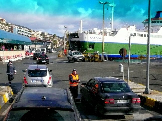 道路はメッシーナ湾に直角に伸びており、海の中に、航行の安全を祈願して建てられたと云う海のマドンナ像を頂く高い塔が、バスの窓にまっ先に飛び込んできた。<br /><br />海岸の道路沿いに桟橋に向かう。<br /><br />たまたま雲が切れ、強い日差しに映った、車の乗船が始まる桟橋の光景は、明るく活気に満ちていた。<br />