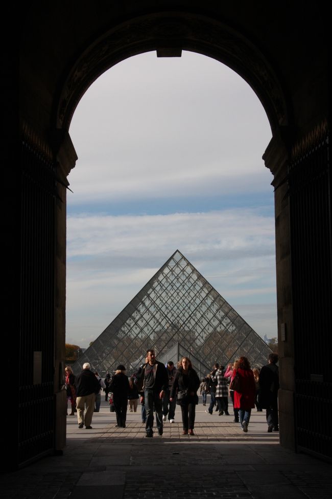 ルーブル美術館　ガラスのピラミッド(方形中庭より）2010.10.31<br />The Louvre Pyramid is a large glass and metal pyramid, surrounded by three smaller pyramids, in the main courtyard of the Louvre Palace in Paris.<br /><br />はじめに<br />私が写真を撮る際に最も大切にしているのは、被写体そのものよりも、そこに反射する光が作り出す輝きと陰影です。それが私が画家クロード・モネを好きな大きな理由です。<br />光の画家モネの「ルーアン大聖堂」連作や「積みわら」シリーズ、新国立美術館で公開された（2010年8月16日まで）の「日傘を持った女」（2枚セットの1枚）、などが特にその光をモチーフにした作品と言われています。<br />私の今回の旅行でも早朝や夕方の撮影で光の捉え方に意を注ぎました。<br />旅行記を読み、写真をご覧いただくときに思い出していただければ嬉しく思います。<br />また旅先の雰囲気（臨場感）を伝えるため、できるだけ人物を写し込むことに心がけました。絵葉書のような写真は好きではありません。<br />────────────────────────────<br />ロンドン・パリ旅行2010⑤パリ <br />毎年１回出かけている海外旅行は一人旅の撮影旅行が多いのですが、今年は3年ぶりに家族で行くことになりました。行き先は家族の希望にしたがって、ヴィクトリア・アルバータ博物館見学とアフタヌーン・ティーを楽しむためにロンドンと初めてのルーブル美術館見学にパリです。<br /><br />2010年10月31日<br />今日はユーロスターでパリへの移動日です。この日から冬時間になるので時計を1時間遅らせた。<br />ホテルでの朝食は摂らずタクシーで出発駅セント・パンクラスへ向かった。早朝のため渋滞もなく30分たらずで到着した。<br />朝食のサンドイッチでも買って車内で食べるつもりでいたが、時間があるので駅構内のカフェでの朝食にした。そこで食べたオーガニック・ハムの美味しさが印象的だった。<br /><br />8時に出国検査。8：26ロンドン出発。<br />ユーロスターは2度目の乗車だが、駆動モーターが前後の車両(機関車）にしかないためか騒音は少ないが、横揺れは意外に大きいことが通路を歩くときに感じられた。<br />ドーバー海峡の海底トンネル通過時は何のアナウンスもなく、外の景色が見えないことに気付かなければいつの間にか通過してしまう。<br />　パリ北駅11：50着（時差1時間）<br />実質2時間半足らずの所要時間である。<br />北駅からタクシーで向かったホテルは、ルーブル美術館見学の便を考えて予約したチュイルリー駅近くのリヴォリー通りにあるSaint James &amp; Albany Hotel。<br />チェックインを済ませて一休みしてから、よく晴れて日差しが強い中をルーブル美術館の中庭を通り、セーヌ川の左岸の川沿いを歩き、ポンヌフをくぐったりしてお目当てのノートルダム寺院へ向かった。バラ窓のステンドグラスを内側から見たいとの家族のたっての希望によるものだ。念願叶ってよかった。<br />一生の思い出に塔にも昇りたいというので、小1時間並んでから狭い螺旋階段を息を切らして登った。50ｍほどの高さの第1展望テラスからはパリの西半分が一望でき、苦労して登った甲斐があった。屋上へは年を考えて登らなかった。<br />降りてくるとノートルダム寺院前の広場では多くの観客を集めてパフォーマンスが演じられていた。<br /><br />帰りは右岸を通って夕焼けを楽しみながらポンデザール（芸術橋）の袂まで歩いた。<br />再びルーブル美術館の中庭を通るころにはあたり一面暗さを増して街灯がともり、ガラスのピラミッドを始め室内の明かりがたとえようのない美しさを醸し出していた。<br />ホテルへ戻る前にオペラ地区の日本食レストランAKITAでこの旅行で初めて焼き鳥と寿司を味わった。<br /><br />2010年11月1日<br />日の出前にセーヌの川べりに行って夜景のような風景を写した。カメラの電池充電器を忘れたため、レンズの作動が不良でボケてしまったが雰囲気だけは捉えることができた。<br /><br />ルーブル美術館の9時からのオープンに合わせてホテルを出た。5分あまりで入り口のガラスのピラミッド前に着くと100人ほどの列ができていた。それでも10分足らずで入ることができた。<br />ルーブル美術館見学は私自身2006年以来でした。今回はレオナルド・ダ・ヴィンチの名作モナリザ（La Joconde）を中心にイタリア絵画の見学に絞った。<br /><br />地下１階のエントランス・ホールには多数のチケット自販機が並んでおり、券を買うのに苦労はなかった。<br />モナリザなどの超人気作品については写真入りの案内板が各所に置かれ、一目で行き先が分かるようになっている。四つ折で縦横30×15cm×4頁のパンフレットも以前のものよりずっと見やすくてよい。<br /><br />モナリザへの直通エレベーターの場所はは知っていたが、初めて来た家族の意向もあって長い階段を歩いて2階まで行った。途中の踊り場にある頭部の無い翼の美人　サモトラケのニケ（サモトラケ島で発見された勝利の女神ニケ）の美しさにしばし見とれた。<br /><br />イタリア絵画を端から見て歩き、中ほどの大きな別室がモナリザの居室（展示室）である。<br />意外に小さい絵であるが本物を前にすると感動もひとしおだ。じっくり見られるほどは近付けないのが少々残念だ。でもこの時刻ではそれほどの混雑も無く、最前列で写真も撮れた。同じ部屋の反対側には畳6枚ほどもの大きさの「カナの婚宴」がありこれも見ごたえがあった。<br />イタリア絵画を一通り見終え、これ以上見ると頭が混乱するからとカフェで休み、家族はルーブル美術館デヴュを無事に果たした。<br />このあとダヴィンチコードで一躍有名になった逆さのピラミッドとルーブル遺跡を見学してカルーゼル口から外に出た。<br />午後は買い物・街歩きで、写真はカメラの電池が尽きてあきらめた。<br /><br />撮影CANON EOS40D EF-S 17/85 IS USM, Nikon Coolpix 5400<br />yamada423<br /><br />写真と説明文をひと通り読んだ後、写真をクリックして更に「この写真の拡大画像」をクリックすると文字や人の表情などがかなり詳細に見られますのでお勧めします。<br />次の写真へ&gt;&gt;　でページが送れます。<br /><br />クチコミ「スリの被害に遭わないための予防策」2011.3.28<br />http://4travel.jp/traveler/810766/tips/<br /><br />現地の日の出・日没時刻はこのクチコミ記事で簡単に調べられます。<br />http://4travel.jp/overseas/area/europe/france/mont_st_michael/tips/10177076/<br /><br />ルーブルの代表絵画モナリザへの近道を紹介します<br />http://4travel.jp/overseas/area/europe/france/paris/tips/10177225/<br /><br />ルーブル美術館のチケット売り場があるガラスのピラミッドの地下階への入り方は下記のサイトに穴場（混雑が少ない）が紹介されているので調べてください。<br />http://france-tourisme.net/p-sight-01/p-01-musee-louvre-entrance.htm<br /><br />☆お気に入りブログ投票（クリック）お願い★<br />http://blog.with2.net/link.php?1581210