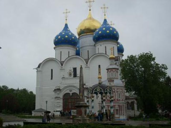 セルギエフ･パサートは、モスクワの北東に環状に連なるロシアの古都群、いわゆる「黄金の環」と呼ばれる11〜16世紀に栄えた宗教都市のひとつであり、1993年ユネスコ文化遺産に登録されている。モスクワからヤロスラーブリ街道を約70km走った距離にあり、黄金の環のなかではモスクワに最も近く、近郊電車（エレクトリーチカ）でも約1時間半で日帰りが可能である。 <br /><br />このロシア国鉄が運営するエレクトリーチカはなかなか面白い。広軌（1,524mm）を採用するロシアの車両は、日本の車両よりもかなり広く、両側に３列ずつ座れる硬い木製の座席がある。ロシア語が不十分な私にはチケットを購入するのが一仕事であるため、早めに駅に行き、座席を確保した。出発間際には大きな車両がほとんど埋まり、座れない人は、入り口横に勝手に座りだした。多くの人は大きな荷物を抱えた出稼ぎ風の労働者だ。電車が発車してしばらくすると、あやつり人形の旅芸人やら、雑誌、衣類、飲み物ピロシキなどの物売り、アコーディオン奏者、宗教家の説法など入替り立代り登場して、去っていった。あたかもロシア現代の世情を演ずる小劇場のようであった。 <br /><br />セルギエフ･パサート駅横にはいかにも地方都市の商店街があり、駅から大修道院へ向かう途中にソヴィエト戦勝記念碑があった。1945年のソヴィエト戦勝記念の火がともされている。 <br /><br />セルギエフ･パサートの町の中心には、トロイツェ・セルギエフ大修道院（聖セルギエフ三位一体修道院）があり、16世紀に築かれた城壁に取り囲まれている。この中には14〜18世紀に建てられた数々の教会があり、その壮麗な建築の調和が興味深い。この修道院を築いたのは、聖セルギウス、彼はモンゴルの支配に抵抗するため、ロシア諸侯の取りまとめ役となり、ドミトリー・ドンスコイ率いるロシア軍が始めてモンゴルに勝利を収め、その後も彼にまつわる奇跡が続き、聖人となった。現在、彼はロシアの守護聖人となっている。 <br /><br />大修道院の中央に位置するウスペンスキー大聖堂はイワン雷帝の命により建てられ、1585年に完成、たまねぎ型をした４つの青いドームの中央に、金色の大きなドームを持つ。モスクワのクレムリンのウスペンスキー大聖堂を模したものである。 <br /><br />大聖堂の北側には、ムソルグスキーのオペラで名高い皇帝ボリス･ゴドゥノフとその家族の墓がひっそりと埋葬されている。ロシアに混乱を招いた皇帝であるためか、雨ざらしで物悲しい。 <br /><br />トロイツキー聖堂は1423年に完成、聖セルギウスの墓所の上に建てられ、彼の棺が教会内に安置されている。また鐘楼はトロイツキー聖堂の横に建てられ、薄緑色に塗られた壁面と、白色の柱、金色の屋根と時計がよく調和しており美しい。ツァーリ宮殿は外壁に特徴がある。セルギエフ大聖堂から修道院出口へは緑に包まれた小道を歩んでいく。 <br />