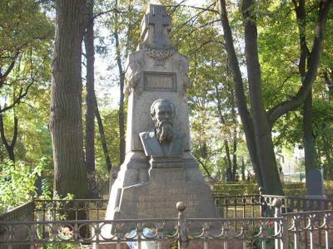 文学愛好家の方には、ここサンクトペテルブルクはドストエフスキーの聖地である。ドストエフスキー（1821−1881）はモスクワで生まれ、17歳の時にサンクトペテルブルクに移った。1849年には社会主義研究会に属していたという罪で銃殺刑を言い渡されたが、直前に死一等を減ぜられてシベリア送りとなった。オムスクで約10年間懲役刑生活を過ごしたあと、サンクトペテルブルクに戻ることができた。その後「罪と罰」（1866年）、「カラマーゾフの兄弟」（1880年）など多くの名作を発表した。サンクトペテルブルクには前述のネフスキー大修道院に彼の墓(写真１）があり、彼が住んだ家は博物館になっている（写真２）。<br /><br />私は長大なロシア文学は苦手で、長い長いロシア人の名前を覚えるのが特に難物であるが、「罪と罰」は若い頃に読んで感銘を受けた。文学ファンや研究者の間では、サンクトペテルブルクの主人公ラスコーリニコフの家や、金貸しの老婆を殺した家、ソーニャの家や盗んだ品を隠した家もすべて正確に特定されているそうで、江川卓氏は「謎解き罪と罰」にその地図を載せている。<br />　<br />この小説が書かれた当時の雰囲気は、大規模な区画整理によって失われてしまっている。ソーニャの勧めで大地に接吻し、殺人を告白して主人公の魂の浄化が行われたセンナーヤ広場（写真３）も、当時のランドマークだったウスペーニエ寺院はソビエト時代に破壊されてしまい、マクドナルド（写真４）が時代の流れを感じさせる。それでも今もここには大きな市場があり、当時の雑然として陰鬱な閉塞感と華麗な都市の裏の世界を垣間見ることができる。<br /><br />続いてプーシキンについて。プーシキン市はサンクトペテルブルクの南、ツァールスコーエ・セロのある町の名であり、また彼の名を冠する通りはサンクトペテルブルクにもモスクワにもあり、彼の像は至る所で見ることができる。サンクトペテルブルクの中心地、ここネフスキー通りにある文学カフェに立ち寄った時のプーシキン(写真７−９）。彼が住んだ家は現在博物館となっている（写真10）。プーシキンについての知識は皆無だったのであるが、グリンカの　「ルスランとリュドミラ」、チャイコフスキー「スペードの女王」、「エウゲニー・オネーギン」、ムソルグスキーの「ボリス・ゴドノフ」などロシアオペラの主要作品が彼の作品を台本にしており、またフランス人との決闘で命を失うなど大変興味をそそられる人物であるため今回彼の足跡をたどってみた。<br />　<br />プーシキンは1799年生まれ、ロシア文学史上最高の詩人と言われ、ロシア人から大変愛されている。急進派として政府と衝突し、監視されるなど波乱の人生を送っている。1831年スウェーデン貴族の血を引く美貌で知られたナターリア・ゴンチャロワと結婚、4人の子をもうけた。（三女マリアはトルストイのアンナ・カレーニナのモデルになった）1835年ナターリアはフランス人の亡命士官、ジョルジュ・ダンテスと出会い、彼が彼女に言い寄ったため1837年プーシキンは彼に決闘を申し込んだ。決闘はペテルブルグ郊外の雪原で行われ、プーシキンはダンテスの撃った弾を右腹部に受けて倒れその2日後に亡くなった。37歳の短い生涯であった。<br />　<br />波乱万丈、という形容がふさわしい人生であったため、プーシキンは多くのロシア人から愛されており、サンクトペテルブルク（写真11）にもモスクワ（写真12）にも彼の像が立ち、プーシキン市やプーシキン広場、プーシキン通りなどが彼の名を冠しているわけである。<br />