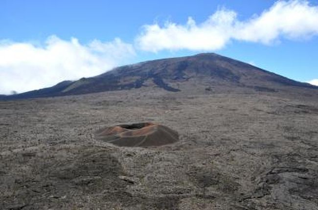 火山島であるレユニオンで今でも活発にその活動を続けるピトン・ドゥ・ラ・フルネーズ。<br />通称ル・ヴォルカン（Le Volcan　英語で言うThe Volcano）。<br />島の南東部に位置し、標高2632m、直径約8kmのカルデラを形成しており、ハワイのキラウエア火山同様、世界で最も活発な活火山の一つでとしても知られている。<br />2010年にシラオス圏谷やピトン・デ・ネージュ等とともにユネスコ世界遺産にも登録された。<br />訪問したのが大晦日であったが、つい数日前の12月9日に噴火したばかりであるとのこと。<br />訪問時は噴煙などは確認できず、いたって穏やかな山に見えたが、歩行場所が限られており、残念ながら火口まで登ることができなかった。<br />せっかくここまで来たのに〜！と悔しい思いをしたが、その雄姿を眺めるだけでも十分な価値はある。<br />先の旅行記でも書いたように、ブール・ミュラの街から火口入口（Pas de Bellcombe)までのアクセス道も実に壮大なスペクタクルが広がっており、ル・ヴォルカンの火口付近も散策することができてまるで火星か月面にやってきたような異空間を体験することができるので、本当にオススメである。
