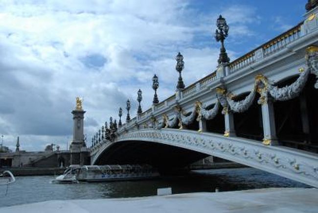 アレクサンドル三世橋の名は、寄贈者であるロシアのニコライニ世の父であるアレクサンドル三世によっている。<br /><br />１９００年に完成した橋は、当時のロシアの力と栄光を誇示しているかのようだ。<br /><br />橋は１９００年のパリ万国博覧会にあわせてアンバリッドとグラン・パレ、プティ・パレの間を結ぶように建設され、パリ市に寄贈された。<br /><br />橋は鋼鉄製、幅４５m、長さ１１５mで３つの関節を持つ単一アーチ橋で、中央に橋脚を建てることなくセーヌ川を一跨ぎしている。<br /><br /><br /><br /><br /><br /><br /><br />