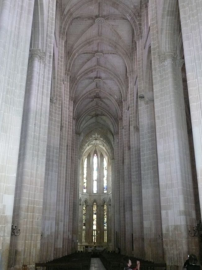 堂内はポルトガル一高い32mの天井を持つ身廊が、身廊の幅が22ｍとやや狭い事もあり、いかにも高く見える。<br /><br />飾りも殆どなく、ポルトガルで最初の建築に使用されたステンドグラスの光だけが、唯一の色彩となっている。<br /><br />直ぐ右脇には「創設者の礼拝堂」が有り、中央のアーチ・ヴォールトの天蓋を囲むステンドグラスの光の下に、ジョアン1世と英国のランカスターから迎えたフィリッパ妃が手を繋いで眠る姿を載せた棺が置かれている。<br /><br />また壁に取り付けられた祭壇にはジョアン1世とフィリッパ妃の3男、かのエンリケ航海王子の棺が置かれていた。<br /><br />堂内を出て王の回廊を突き当り、左に進むと、アーチ・ヴォールト形式の天井の、だだっ広い柱が一本もない部屋に出る。<br /><br />なぜか「参事官室」と名の付くこの部屋の正面の十字架の下に、第1次世界大戦とソマリア戦の無名戦士の墓が有り、銃を片手にした二人の兵に守られている。<br /><br />近づいて見ると、十字架に架けられているキリスト像は片腕の肘から先と両足の膝下が無い。<br />第1次世界大戦末期にフランスで偶然発見されたらしい。<br /><br />さてこのだだっ広い部屋が建設された当時、柱が1本もない天井なんか落ちるに決まっていると誰も部屋に入りたがらなかった。<br /><br />そこでこの部屋を建設したＡ・ドミンゲスは自ら３日３晩この部屋で過ごし安全を証明してみせ、部屋の一角を舌を出して得意げに見下ろす自らの顔で飾った。<br /><br />1508年、部屋の東の壁面に取り付けた、キリストの苦難の場面を表したステンドグラスが美しい。<br /><br /><br />ポルトガル旅行マップ<br />http://www.geocities.jp/tshinyhp/portugal/portugalmap/frameportugalmap.html<br /><br />バターリャ勝利の聖母マリア修道院旅行マップ<br />http://www.geocities.jp/tshinyhp/portugal/portugalmap/batalha/framebatalha.html<br /><br /><br />