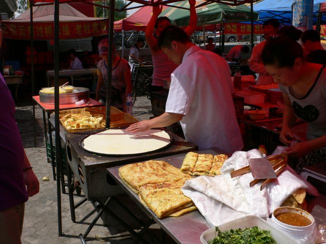 ハルビンの街中を散歩しているとき、美味しそうな屋台を見つけました。<br />なかでも直径50センチ以上あるどでかいたまご餅が圧巻！<br />別のお店でおかずを買ってきて、一緒に巻いてもらったり、<br />そのままご飯代わりにおかずと一緒に食べたりと用途もいろいろです。<br /><br />料理名を聞いたら「鶏蛋餅」といわれました。<br /><br />