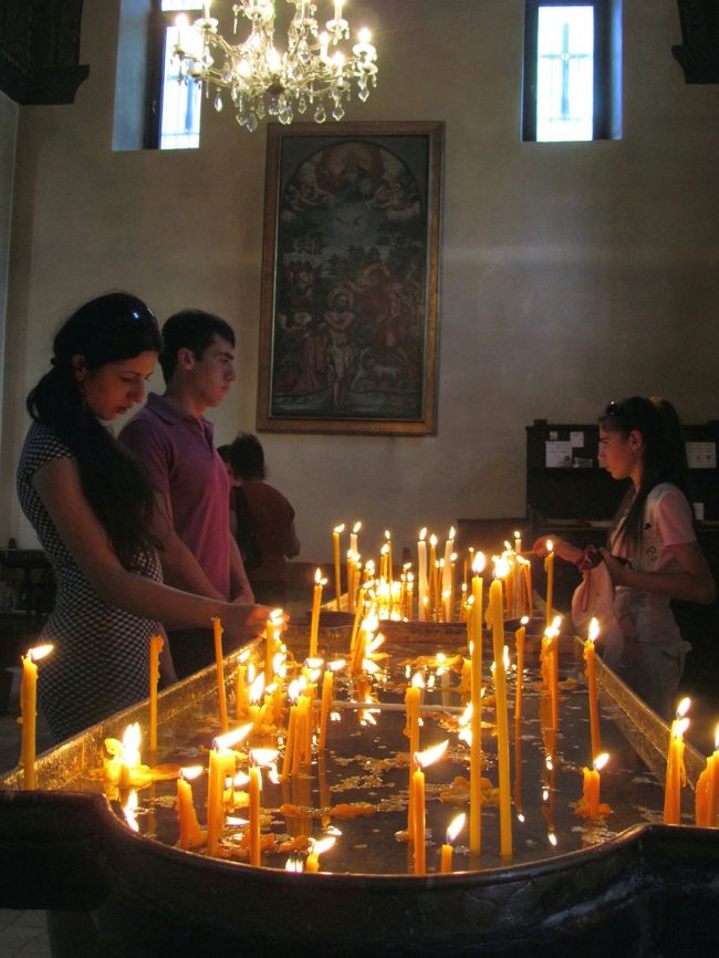 キリスト教の習慣は詳しく知りませんが、今まで旅行してきた東欧諸国では、例えばルーマニアやブルガリアの正教会では、蜜蝋のろうそくに火を灯して祈るとき、生者と死者のどちらのために祈ってもよいのですが、ろうそく立ては別々にありました。<br /><br />ルーマニアでは、生者のためと死者のためのろうそく立てはたいてい同じところに並んであって、同じような形をしていて、VII（＝生者）とMORTI（＝死者）といったように書かれた文字で区別されていました。<br />ブルガリアでは、ろうそく立ての高さが違っていて、低いろうそく立てが死者のためのものでした。<br />これらの情報は現地ガイドから教えてもらいました。<br /><br />その後に訪れたウクライナやその他の国々では、現地の人に聞くチャンスはなかったのですが、このように生者と死者のためのろうそく立てはきっと分かれていて、信者には一目瞭然だったろうと思います。<br /><br />関連の写真<br />http://4travel.jp/traveler/traveler-mami/pict/13869271/<br />関連の旅行記<br />「2007年ルーマニア旅行第18日目(1)：通算5日目のブカレスト観光」<br />http://4travel.jp/traveler/traveler-mami/album/10241136/<br /><br />関連の写真<br />http://4travel.jp/traveler/traveler-mami/pict/14635973/<br />関連の旅行記<br />「2008年ブルガリア旅行第４日目(1)：最近の聖人ババ・ヴァンガの教会とピリン山脈」<br />http://4travel.jp/traveler/traveler-mami/album/10277008/<br /><br />関連の写真<br />http://4travel.jp/traveler/traveler-mami/pict/15917502/<br />関連の旅行記<br />「2008年ブルガリア旅行第12日目ソフィア(3)：古代・中世・近代の香りの教会群」<br />http://4travel.jp/traveler/traveler-mami/album/10323066/<br /><br />教会の中はある意味、美術品の宝庫であり、興味深くて美しいものがたくさんあります。<br />その中でもろうそく立てに注目するようになったのは、ルーマニアやブルガリアでそのような話を聞いたせいもあります。<br />でも、信者なら、教会に足を踏み入れれば、たいてい、教会内の売店でろうそくを買い、火を灯して捧げて祈ります。<br />私たちが神社にお参りするときに、鐘を鳴らしてお賽銭をあげるのと似たようなものでしょう。<br />だから、ろうそく立ては、イコノスタシス（信者の空間と祭壇を仕切るイコンの壁）やイコン同様、教会の中で、とても重要で身近な部分といえます。<br />なので、撮影が許されるなら、教会の中でろうそく立てを撮りたくなるのは当然なのですが、グルジアとアルメニアの教会で見たろうそくは、デザイン的にもとてもすばらしく、凝ったものが多かったので、余計にそそられました。<br /><br />そこで、ろうそく立ての写真だけ集めて一つの旅行記にまとめてみることにしました。<br />また、ろうそくの神秘的な光に誘われて写真も撮ってしまったので、その写真もまぜました。<br /><br />ちなみにグルジアでは、現地ガイドから生者のためのろうそく立てと死者のためのろうそく立ての見分け方を教わりました。<br />ろうそく立ての前にはたいていイコンがあります。<br />それぞれのイコンに描かれた聖者は、それぞれに特定の守護する対象がある、守護聖者です。<br />だから、信者は祈りたい聖者のイコンの前にろうそくを立てて祈るのです。<br />そんなイコンの中で、キリストの十字架磔のイコンの前にあるろうそく立ては、死者のために祈るときだけのものなのだそうです。<br />なぜかというと、十字架磔のキリストは死者だからだそうです。<br />それ以外のろうそく立てでは、生者のためでも死者のためでもどちらのために祈っても構わないそうです。<br /><br />※2011年コーカサス３カ国旅行の旅程一覧とルートマップはこちら。<br />簡易版「2011年コーカサス３カ国旅行プロローグ（旅程一覧）地図付」<br />http://4travel.jp/traveler/traveler-mami/album/10584724<br />詳細版「2011年コーカサス３カ国旅行の詳細旅程（写真付き）」<br />http://mami1.cocolog-nifty.com/travel_diary1/2011/07/2011-1ab0.html <br />