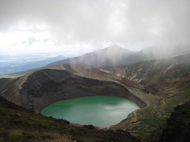 (写真は蔵王お釜）<br /><br />やっと、週末といい天気が重なり、登山日和となりました。<br />なるべく負担なく登れる山、ということで蔵王＆月山に決定。<br /><br />9/23東京−(新幹線)−白石蔵王＝(定期バス）＝刈田山頂･･熊野岳山頂･･地蔵岳-(ﾛｰﾌﾟｳｳｪｲ)-蔵王温泉（泊）<br />9/24温泉＝山形駅＝(高速バス)＝鶴岡＝(定期バス)＝羽黒山（泊）<br />9/25羽黒山＝月山八合目･･月山山頂･･姥沢＝西川＝(高速バス)＝山形−(新幹線)−東京<br />（予算）交通費、新幹線約￥20,000　バス代ﾛｰﾌﾟｳｪｲなど約10,000<br />　　　　宿泊代2泊4食約14,000ほど<br /><br />9/23　朝のいい天気はどこへやら、11時に刈田山頂に着いたその時から一面ガスに覆われた。<br />　視界は悪いが、お釜を右に見て､ただ真北へ尾根伝いに行けばいい。<br />　初めてのコースだが、迷いようがないルートだ。<br />　40分も歩いたろうか、避難小屋があった。<br />　ガスで見通しは悪いがここを左手に進めば熊野岳頂上のはずだ。<br />　だが、頂上は平べったくどこがテッペンだかわからない。<br />　神社や記念碑らしきものがいろいろ建っている。<br />　とりあえず三角点を探し、地蔵岳を迂回し、ロープウェイ乗り場から蔵王温泉へと一気に下る。<br />　　頂上からガスの中、雨からヒョウも混じり景色を楽しむどころではありません。そういえば、頂上で出会った革靴､Yシャツで登ってきた太めのオジさんはどうなったか少し気掛かりです。<br /><br />　昨日予約した宿には14時すでに到着、下界はすでに大雨です。<br />　温泉では旅館湯と共同上湯、下湯と楽しみます。<br />　泉質は源泉が同じせいか、宿もどこも同じ白濁の硫黄温泉でした。<br /><br />&lt;山の天気＞<br />　晴れるか雨（雪）になるかは、山では時に生死を分けます。<br />大気の含むことができる水分量は気温によって変わります。<br />気温が高いほど水分を多く含むことができる(雨/ガスにならない)ので、太陽がテッペンに来るまで気温は上昇しますから、朝晴れていれば、午前中はほぼ雨は降らないと思っていいことになります。<br />　つまり山は晴れた日の早朝に登り、頂上で昼飯を食べ、気温が下がり始める午後一番で降りてくれば、まず雨やガスには遭わないですむということになります。1週間前にはほぼ山の天気予報が出ますから、それに合わせて日程を組みましょう。山の気温は100ｍ高くなる毎に0.6度下がります。<br /><br />（続）羽黒山・月山へ<br />　　　　http://4travel.jp/traveler/janal/album/10606005/