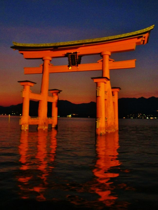自然の重みで建つ大鳥居 <br />海の中に建つ大鳥居は宮島のシンボル。実はこの大鳥居の根元は海底深く埋められているわけではなく、自分の重みだけで建っているのです。それなのに台風や地震がきてもびくともせず、動いたり、倒れたりしないのはなぜでしょう。その秘密の1つは鳥居上部の島木は箱形の造りで、中にこぶし大の玉石約7トンを詰めて“おもし”にしているから。また主柱・袖柱あわせて安定感のある6本足とし、柱と屋根の交差する部分には特殊な造りのクサビがほどこされて、柱と屋根の動きやひずみなどを自然に吸収。海底部分は松材の杭を打って地盤を強化したうえで、その上に布石を並べて基礎の代わりとしています。まさに先人の知恵のたまもの。数百年前にこれだけの仕掛けを行っているわけですから、改めて驚かされます。大鳥居の高さは約16メートル、主柱の周囲は約10メートルもあり、しかもクスの自然木。クスの木は、腐りにくく虫に強いためです。昭和25年に水に浸かる下の部分が新しいクスの木に取り替えられました。◎大鳥居に掲げられている扁額は、有栖川熾仁親王の染筆。また鳥居の屋根の東西には、「太陽」と「月」が描かれています。風水では北東を鬼門の方位とするため、太陽は鬼門封じのためともいわれます。(http://www.miyajima-wch.jp/jp/itsukushima/column.html より引用)<br /><br />宮島については・・<br />http://www.miyajima-wch.jp/<br /><br />夜の遊覧はライトアップされた厳島神社、五重塔、多宝塔を見ることが出来ます。満潮時間には大鳥居をくぐる事もあります。(下記より引用)<br /><br />宮島遊覧観光については・・<br />http://yu-ran.com/index.html<br /><br />前回(2009年12月11・12日)の旅行記は・・<br />宮島-1 厳島神社 朝一番に参拝 ☆人と神々が共存する島 http://4travel.jp/traveler/maki322/album/10412384/<br />宮島-2 厳島神社の大鳥居 ライトアップ ☆観光船で海からも<br />http://4travel.jp/traveler/maki322/album/10412457/<br /><br />涼やか絶景 夫婦のんびりふたり旅5日間(山陰・山陽)<br />1日目 9月8日(木)<br /> 東京駅(10:10発)=<新幹線N700系のぞみ25号・グリーン車>==広島駅(14:06着)=平和記念公園=宮島口=○安芸の宮島(約120分)==◎厳島神社(拝観料込み)==宮島島内にて「カキ料理」の夕食==宮島==<宮島ナイトクルージング・約30分>==宮島口==広島<泊/21:30頃着><br />【バス走行距離:約44km】<br />【宿泊先:グランドプリンスホテル広島 082-256-1111】 <br />http://www.princehotels.co.jp/hiroshima/<br /><br />