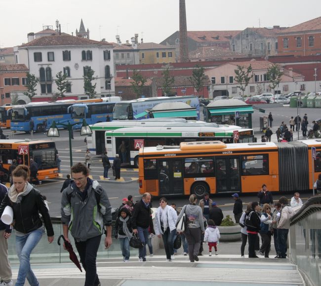 2011.10.19　　13：21<br />サンタ・ルチア駅前のカラトラーヴァ橋からローマ広場を望む。<br />View of Piazzale Roma on Ponte Calatrava<br /><br />ベネチア「本島」に入ったバスのほとんどすべてはここに到着する、まさしく玄関です。「本当」です（笑い）<br /><br />この旅行記にはヴェネチア大運河Canal Grandeに架かる4つの橋が登場します。サンマルコ側からアカデミア橋、リアルト橋、スカルツィ橋、カラトラーヴァ橋（正式名：コンスティテューション橋）です。<br /><br />先に公開した「2011ヨーロッパ鉄道の旅12日間/概要」<br />http://4travel.jp/traveler/810766/album/10617323/<br />に続いて個別の都市ごとの旅日記に基づいた写真旅行記の連載を進めます。<br />第４回はサンタ・ルチア駅、ローマ広場界隈です。<br /><br />2011.10.19<br />明け方の空には月が残っていたが雲がかなりあった。夜中に一度目が覚めたが、今朝はアラームをセットせず、７時に目覚めてちょうどよかった。<br />８時ごろに朝食、出かける前に絵葉書を何枚か書いた。<br />今日はライナーを外したハーフ・コートで９時半ごろ出かけた。<br />昨夜のリストランテのお姉さん?がカラフルな虹色のセーターで開店準備をしていたのでボン・ジョルノ。<br />アカデミア橋を渡り、南側のドルソドゥーロ地区を街歩きしてからサンタ・マリア・デッラ・サルーテ教会へ入った。この教会の大きなドームを昨日の夜明けにアカデミア橋から感激しながら写したのであった。<br />内部はきわめて簡素でカラフルなステンド・グラスの大聖堂を期待するとがっかりするだろう。<br />教会裏のサルーテからヴァポレットでサンタ・ルチア駅前のフェロヴィアへ行き、駅の窓口で翌日の列車のeチケットを切符に換えた。駅構内の列車を見に行くとEurostar Italiaもあった。<br />駅前は大勢の観光客で賑わっていた。大運河に架かるスカルティ橋からの眺めがよい。<br />昼近くになり、駅構内のBUFFETで焼きたてのピザを買い、水辺の階段に腰を下ろして食べた。近くにいた親子（母子）はイギリスから来たそうで折り紙をして遊んでいた。Origamiを知っていた。<br />駅の対岸のパパドーポリ公園、駅とローマ広場を渡すカラトラーヴァ橋などを散策してからヴァポレットでアカデミアへ戻った。サント・ステファーノ広場では恵比寿で展示会を開いたことのあるという女性写真家親子との交流があり、お互いにPRカードや写真はがき交換をした。<br />ホテルで一休みしている間に明るくなってきたので４時過ぎに出かけた。アカデミア周辺の店を覗いたり、サルーテからサン・マルコへ渡って再びサン・マルコ広場周辺の店を見たりして要望されたヴェネチアン・グラスのネックレスをやっと見つけた。これでお土産のことはきりがついた。<br />サン・マルコ寺院の裏手の狭い道沿いは12年前のツアーの自由行動時に夕食を食べた店があった地域のような気がしたが、定かではない。<br />時間は少し早いが空が暗く雨の心配もあるので夕食のリストランテに入った。<br />PIZZARIA RISTORANTE FALCIANI<br />前菜は昨日のランチで美味しかったラザニア、メインは注文の手違いで供されたイカの墨煮。<br />結果的にはヴェネチアの名物料理の「セッピアの墨煮」が食べられて正解でした。<br />帰る頃にはしっとりと小雨で濡れたサン・マルコ広場の夜景が幻想的な雰囲気を醸していた。<br /><br />旅行記2011①②③は前記の概要編<br />http://4travel.jp/traveler/810766/album/10617323/にURL<br />の記載があります。<br /><br />撮影CANON EOS40D EF-S 17/85,EF-S 55/250<br />参考資料　わがまま歩き　イタリア<br />　　　　　まっぷるイタリア2011-12<br />　　　　　世界の100都市　ヴェネチア<br />参考情報　ベネチアのスーパーマーケット<br />　　　　　http://www.amoitalia.com/venezia/supermarket.html<br /><br />第４回公開　2011.12.3　<br />毎週土曜の夜に新編公開予定「土曜旅画劇場」（入場無料）<br /><br />お気に入りブログ投票（クリック）お願い<br />http://blog.with2.net/link.php?1581210