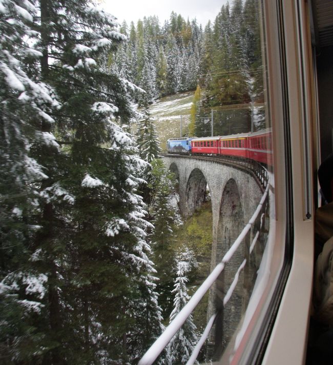 Samedanで乗り換えてアルブラ線に入ると、しばらくして沿線屈指の名所Predaの高架橋と曲線トンネルに差し掛かる、アルブラ線の普通列車<br />2011.10.20　　16：41<br /><br />先に公開した「2011ヨーロッパ鉄道の旅12日間/概要」http://4travel.jp/traveler/810766/album/10617323/に続いて個別の都市ごとの旅日記に基づいた写真旅行記の連載を進めます。<br />第7回は今回の鉄道の旅のハイライトであるスイスの世界遺産　アルブラ・ベルニナ鉄道です。<br />2011.10.20<br />ティラーノ駅は到着したイタリア国鉄の駅と、ベルニナ鉄道の起点のティラーノ駅とは20ｍしか離れていない。　ランチの前に本日の宿泊地クールまでの切符を買い時刻表をプリントしてもらった。<br />人気のベルニナ急行Bernina Expressではなく、景色の撮影に好都合の鈍行(普通）列車を選んだ。急行より10ﾕｰﾛ安い48ﾕｰﾛ。<br />撮影のために窓が開けられるのも好都合だ。急行は不可。<br />ティラーノ駅はイタリアにあるのでユーロでOK。<br />イタリア北部のスイス国境の街ティラーノを出発したベルニナ鉄道（正確にはレーティッシュ鉄道ベルニナ線）の赤い列車は何度もループを描きながらベルニナ山4049ｍの中腹の標高2253ｍの最高地点　Ospizio Berninaを目指す。この地点にある湖はすでに雪に覆われ、白緑（ﾋﾞｬｸﾛｸ）の水面が草津白根山のお釜の色を思わせる神秘的な美しさだ。<br />標高が高いところでは、黄葉したカラマツが白く雪化粧をして秋の終わりを告げ、アルプスの山々はどこも白く雪を戴き、まもなく冬が近いことを知らせる。<br />列車は直線に走ることがほとんどないため、窓から前後の車両が右に左にとカーブするのがよく見えて風景にとけこんだ赤い列車の撮影には好都合だ。<br />サンモリッツに近いPontresinoとSamdenで乗り換え、アルブラ線に入ると、しばらくして沿線屈指の名所Predaの高架橋と曲線トンネルに差し掛かる。一瞬に通過してしまったので思うような写真は撮れなかった。（表紙写真）<br />クールまでの車窓はこれぞスイスといった景色の連続で、見ているだけでも飽きることがない。<br />車窓から見下ろす山の上に建つ教会の白い塔が夕日に染まり、一日がかりでイタリアからやってきた旅人をあたたかく迎えてくれるようで、心温まる。<br />クール駅には定刻の18：03ちょうどに到着した。スイスで最も古い町といわれるが、この地域の中心都市で駅も街並みも立派だ。<br />駅のコインロッカーにキャスターケースを預け、カメラバッグ一つでホテルに向かった。<br />ホテルは駅から10分ほどのAmbiente Hotel Freieck 。<br />部屋は暖かい色使いで、この旅行では初めてのバスタブもあり、ゆっくり休めそうだ。<br />早朝（夜明け前）にヴェネチアのホテルを発って、すでに12時間以上が経っている。<br />2011年10月20日(木Thu）の列車運行記録<br />Venetia7:00 EC9704→Verona8:07→Brescia8:43→Milano9:30  Eurostar City32.5ﾕｰﾛ(ﾈｯﾄ)<br />　<br />Milano10:35R2556→Lecco11:10→Bellano11:35→Colico12:01→Sondrio12:23→Tirano12:50 10.75ﾕｰﾛ（ﾈｯﾄ） 以上はイタリア国鉄TRENITALIA<br /><br />Tirano13:40 R1656→Pontresino15:50/16:02 R1956→Samden16:08/16:17 RE1156→Tiefencastel→Chur18:03　 48ﾕｰﾛ（現地購入）以上はスイスのレーチッシュ鉄道Rhaetian Railway<br />出発時刻の次の記号･番号は列車番号で時刻表による。<br />時刻は時刻表ではなく実際の時刻です。<br /><br />なおPontresino→Samden→Tiefencastel→Churの区間は氷河急行（グラーシャー・エクスプレスGlacier Express)との共通区間です。<br />世界で一番遅い急行列車The slowest express train in the worldと自慢げに言われています。<br />Glacier Expressを氷河特急と誤訳したのは誰でしょうね。<br /><br />撮影　CANON EOS40D EF-S 17/85 ,EF-S 55/250<br />参考資料<br />Rhaetian Railway&quot;Great railway experiences in the ibex country&quot; Summer 2011<br />BARTHOLOMEW &quot;ROAD ATLAS EUROPE&quot;<br /><br />＜今夜の宿泊地クールChurについて＞<br />約5000年の歴史を誇りスイス最古の町ともいわれるグラウビュンデン州の州都。ケルトの集落からローマに統治され、その後は司教領として栄えてきました。今でもカテドラル（大聖堂）を中心として豊かな文化遺産や史跡が数多く点在しています。中世の町並みをそのまま残す旧市街は城壁に囲まれた自動車の入れない歩行者天国。5～10月の毎土曜日には周辺の山々から特産品を持ち寄って素朴な市場が開かれます。若者が集まるトレンディスポットも多いクールは、約500軒の個性的な店舗のあるスイス屈指のショッピング天国です。また数々のポストバス路線や氷河特急、ベルニナ特急など絶景自慢の鉄道路線の発着点としても有名。多くの人が周辺の小さな村やマウンテンリゾートへのエクスカーションを楽しんでいます。<br />http://www.myswiss.jp/jp.cfm/area/offer-Destinations-01Graubuenden-206927.html<br /><br />旅行記2011①～⑥は前記の概要編http://4travel.jp/traveler/810766/album/10617323/にURLの記載があります。<br /><br />■参考情報　2020.1.20<br />スイス鉄道(スイス国鉄：SBB) チケット予約をわかりやすく解説<br />https://urtrip.jp/swiss_train_ticket/<br />スイス国鉄(SBB)のチケットを日本から安くオンライン予約・購入する方法、スイス現地での電車の乗り方をわかりやすく解説します。<br /><br />スイス国鉄には早割チケット「スーパーセーバーチケット」(Supersaver ticket)があり、運賃が最大50%OFFになります。<br />
