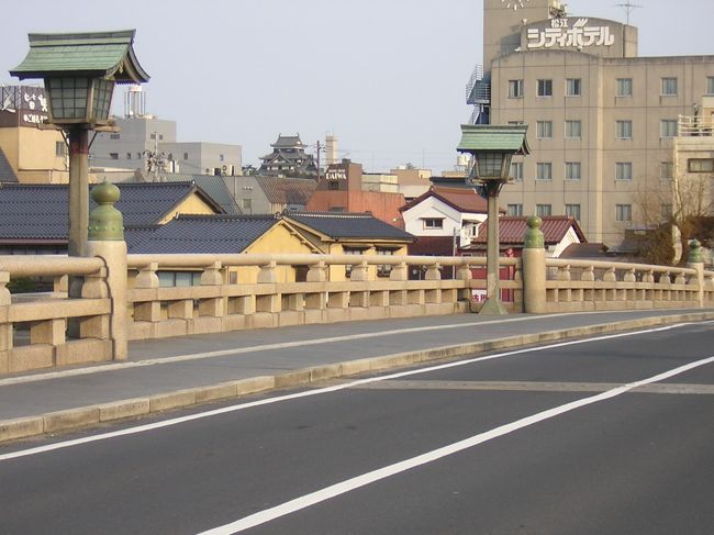 　松江大橋は慶長13年（1608年）、堀尾吉晴公が月山富田城から松江に移城の際に築城の資材を運搬するために造られたとされ、現在は17代目になる。大橋川に架かる橋で、全長138m。昭和12年（1937年）に完成し、御影石の欄干と唐金の擬宝珠が歴史と風情を漂わせる造りとなっている。松江大橋と呼ばれるようになったのは、明治７年（1874年）改架の11代目からで、それまでは「白潟橋」、「カラカラ橋」などと呼ばれていた。<br />　大橋川に架かる橋は宍道湖側から宍道湖大橋、松江大橋、新大橋、くにびき大橋と4橋があり、美しい宍道湖が見渡せる。<br />（表紙写真は松江大橋）