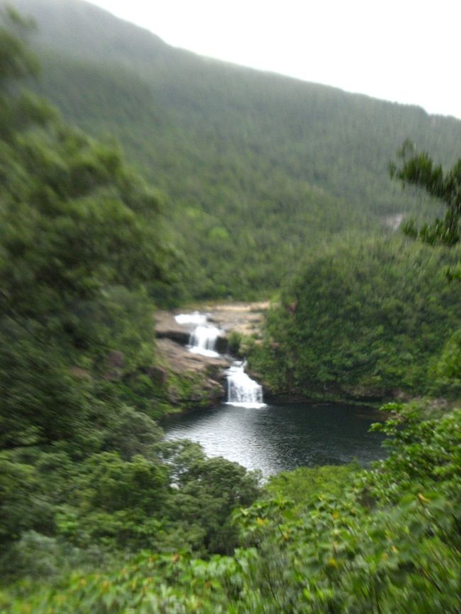 今回の西表訪問では未訪問の場所へ行こうと決めていて、その一つが“パナリ島”＝「新城島」であることは「その１。」で書いた。<br />2つ目は、実は「マリュドゥの滝/カンピレーの滝」。<br />石垣から日帰りでも行ける、超ポピュラーな観光スポットであることは広く知られているが、それだけに安直で俗っぽいイメージがあって、これまで避けてきた。<br />しかしもともと｢滝」が好きということもあり、やっぱり一度は行っておこうというわけで、西表10回目にして初訪問。<br /><br />浦内川の観光船に乗って、終点の軍艦岩からは徒歩。<br />ポピュラーなお気楽コースと思いきや、前夜の雨のせいもあって足場が悪く、草が茂っている箇所もありで、サンダルやハイヒールで行ける場所ではない。<br />軍艦岩から20分ほどで展望台に到着。<br />ここから見えるのが「マリュドゥの滝」だ。距離はかなりあるが、それでも水量豊富な滝の迫力は味わえる。<br />『マリュドゥ』は「丸い淀」のこで、この滝が円形の滝壺を持つことからこの名を冠したそうだ。<br />ここで引き返す人も多いが、それではもったいない。もう一つの「カンピレーの滝」まであと一息である。<br /><br />マリユドゥの滝からさらに約５分、カンピレーの滝に到着する。<br />およそ200mに渡って、急流の川のような滝が現れる。およそ｢滝｣のイメージではないが、巨大な岩盤の上を水が流れる景観は、川とも違い不思議な光景だ。<br />『カンピレー』とは「神が座るところ」という意味だそうだが、確かにこの巨大な岩盤は神様の造形物と昔の人が考えたのもうなづける。<br /><br />岩盤には“ポットホール”と呼ばれる穴が随所に見られる。これは、窪みに入った石が水流で転がり岩盤を削ってできた穴。かなり大きなものもあり、一体どれくらいの年月がかかったのだろうと思いを馳せるのも楽しい。<br /><br />メジャーな観光スポットだからこそ、朝一番の船に乗って大正解。ほぼ一番乗りで人気のない開放感を味わえた。<br /><br />「超メジャー＝安直で俗っぽい」というイメージがあったが、やはり行ってみれば発見はあり、メジャーになるだけの価値はあると再認識。<br />絶対外せない、とは言わないけれど、西表に滞在するなら一度は行っておいた方がいいと感じた。<br /><br />【追記】<br />新城島＝パナリ島の歴史の中に、「パナリ焼き」という焼き物がある。<br />200年前まで焼かれていたといわれる土器で、素地の中に貝の粒を混ぜて露天で焼かれているのが特徴。<br />その歴史や製法等について正確なことはわかっていないらしいが、その復元運動に参加した陶芸家が西表は白浜集落で喫茶店(？）を営んでいる。<br />陶芸家と言うとなにやら近寄りがたいイメージがあるが、非常に気さくでどこか浮世離れしたおばあである(笑)。<br />パナリ焼きや「アートフィッシュ」の話を聞きながらお茶を飲むのも良いものだ。<br />「アートスペース IKEI」http://www.yasigani.net/omiyage/ikei/index.htm