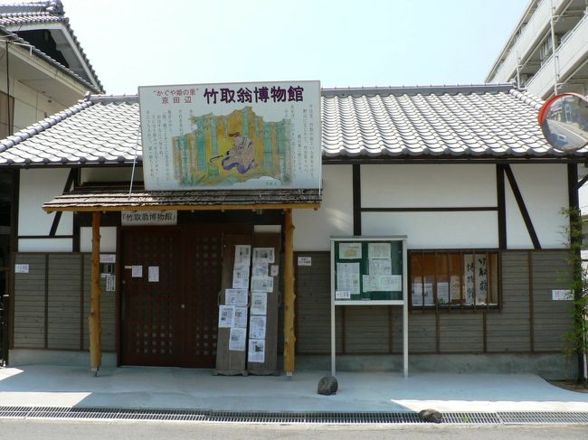 京田辺市には竹取物語の舞台となったとされる山本駅跡、月神信仰に基づく月読神社、継体天皇の筒城宮、などかぐや姫につながる歴史遺産が多い。種々文献などの研究をされ“かぐや姫の里”は京田辺であると確信される竹取翁博物館館長の小泉芳孝さんの熱意によってかぐや姫の里・京田辺に関する資料などを展示する博物館が今年２月に開館し、かぐや姫ファンたちの関心を集めている。古民家を再生利用した博物館には「かぐや姫」に関連する資料のほか日本や世界の民俗考古資料などが展示されている。竹取翁博物館は京田辺市だけでなくアジアの新たな歴史文化文学などの研究の拠点のひとつになるかもしれない。竹取翁博物館の詳細は下記ブログが詳しい。<br />（竹取翁博物館の詳細）<br />”かぐや姫の里”京田辺『竹取翁博物館』：koiさんの旅行ブログ--http://4travel.jp/traveler/koi/album/10620222/<br />&quot;かぐや姫の里”京田辺竹取翁 博物館 ２０１２年２月オープン：koiさんの旅行ブログ<br />--http://4travel.jp/traveler/koi/album/10645185/<br /><br />竹取翁博物館―――http://taketori.koiyk.com/okina-hakubutu.html<br /><br /><br />竹取翁博物館は近鉄、ＪＲの三山木駅（みやまきえき）から徒歩２−３分の便利な場所にある。<br />三山木駅（みやまきえき）前のバスターミナルからは、同志社京田辺キャンパス（同志社大学、同志社女子大学、同志社国際中学校・高等学校）方面へのバスの発着が多 く交通の便も良い。<br />（写真は竹取翁博物館の案内）<br />