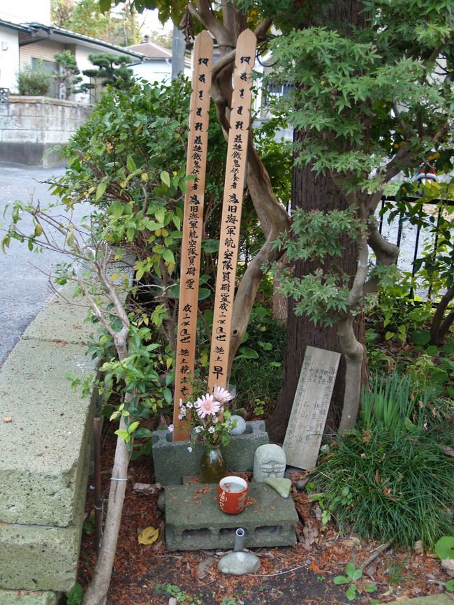 横浜市金沢区にある称名寺市民の森から下りてくると、称名寺仁王門の右脇に出る。称名寺仁王門脇に新しい2つの卒塔婆が立てられて戦死者の墓のようなものがあるのだが、石塔などは何もない。これまで、国内を巡っても戦死者の墓に石塔が建てられていないことなど1度もなかった。その前の家で尋ねてみた。<br /> 昭和18年(1943年)5月1日に群馬の飛行場から荷物を運んで戻ってきた99式艦上爆撃機に追浜飛行場(現日産追浜工場)から着陸許可が下りずに上空を旋回していたが、燃料切れになり、海までは遠いので称名寺横の畑(現在は空き地で草原になっている)に着陸しようとしたが、そこには畑仕事の人影が見え、躊躇しているうちに、仁王門の右脇の木に引っ掛かり、墜落し、パイロットら2人の搭乗員は亡くなられたのだという。何と痛ましいことであろうか。<br /> その後、亡くなられた2人の身元も判明し、墜落した命日にはこの家のおじいさんが称名寺のお坊さんを呼んで毎年供養していて、このおじいさんが亡くなった後もこの家の家族が引き継いで供養しているのだという。それで石塔が建っていないことに納得できた。2人の搭乗員のうち、1人は田舎に墓(石塔)が建てられ、遺族が墜落地のこの地にも訪れ、供養してくれていることに感謝し、お礼を述べに来られるという。もう1人は遺族がおられなく、墓は地元の人たちが建て弔ったようだとも言われている。<br /> なお、99式艦上爆撃機とは皇紀2599年(昭和14年(1939年))に制式採用された海軍の艦上爆撃機(空母から発着艦する)で、真珠湾攻撃などで活躍した。車輪が格納できないタイプでいかにも旧式な感じがする。翌、皇紀2600年(昭和15年(1940年))に制式採用された海軍の零式艦上戦闘機(零戦)は1人乗りで、離陸後には車輪が機体に格納された。こちらは、私のように、小学生の頃の漫画雑誌の特集は連合艦隊の艦船や戦闘機などばかりで、それを読んで育った世代でなくても、誰もが知っている名前であろうか。<br />(表紙写真は墜落現場跡の供養)