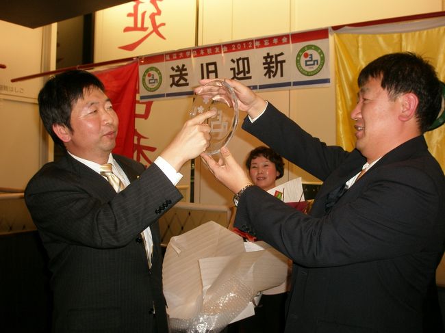 2012年12月8日(土)夜、御徒町の本格中華料理店・延吉香で延辺大学日本校友会の定期総会および忘年会が開催されました。<br /><br />校友会HP http://www.ybuaaj.com/home<br /><br />延辺大学に縁のある日本人会有志も参加。民族舞踊、歌謡、大抽選会等で大変盛り上がりました。<br /><br />景品にはディズニーリゾートペアチケット。当たったのはなんとあの・・・<br /><br />写真は新会長の金吉山さん(左)より任期を終えた胡林旧会長へ記念品を贈呈しているところです。<br /><br />指で数えているマークの数は6つあり、胡会長の在任期間・6年間を示しています。長い間、お疲れさまでした。<br /><br />NPO法人日中韓観光協力機構 ←延辺大学の日本での留学生受付窓口<br />http://jcktcocolumn.blogspot.jp/2013/10/2014.html