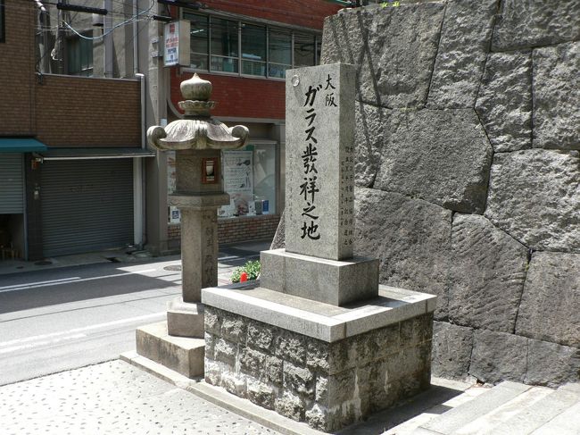 地下鉄･南森町駅、 ＪＲ東西線･大阪天満宮駅から 南に２００ｍ、天神橋筋商店街の南 大阪天満宮の正面西側に“えびす門”があり門の外に「大阪 ガラス発祥の地」と刻まれた石碑が建っている。<br />１９７９年に大阪硝子製品協同組合の設立３０周年を記念して建立されたとのことで日本に１５４９年にフランシスコ・ザビエルが周防の大名、大内義隆に贈ったガラスの鏡や遠めがねなど ガラス製品の渡来がきっかけとされている。 長崎にガラス製法が伝わって日本でもガラスが作られるようになり天満に吹きガラスの職人が誕生したのは 播磨屋(久米清兵衛)が長崎でガラス製法を学び天満の玉屋で珍しい色のガラス玉細工を始めたのが最初で日本のガラス工業界は実質的に大阪が始まり言われているとのこと。 <br />天神橋筋商店街（てんじんばしすじしょうてんがい）は、大阪市北区にあるアーケード商店街で南北２．６キロメートル、６００店の日本一長い商店街。「３丁目商店街」は２００６年５月に「がんばる商店街７７選」に選ばれている。江戸時代に日本の物流で主要な役割を果たした「天満青物市場」を中心として発達し「十丁目筋商店街」といわれ、現在も地元では十丁目（じっちょめ）と呼ばれている。十丁目とは江戸時代の町名「天満10丁目」のことで天神橋北詰がちょうど１０丁目にあたることに因むとのこと。<br />（写真は「大阪 ガラス発祥の地」碑）<br /><br />