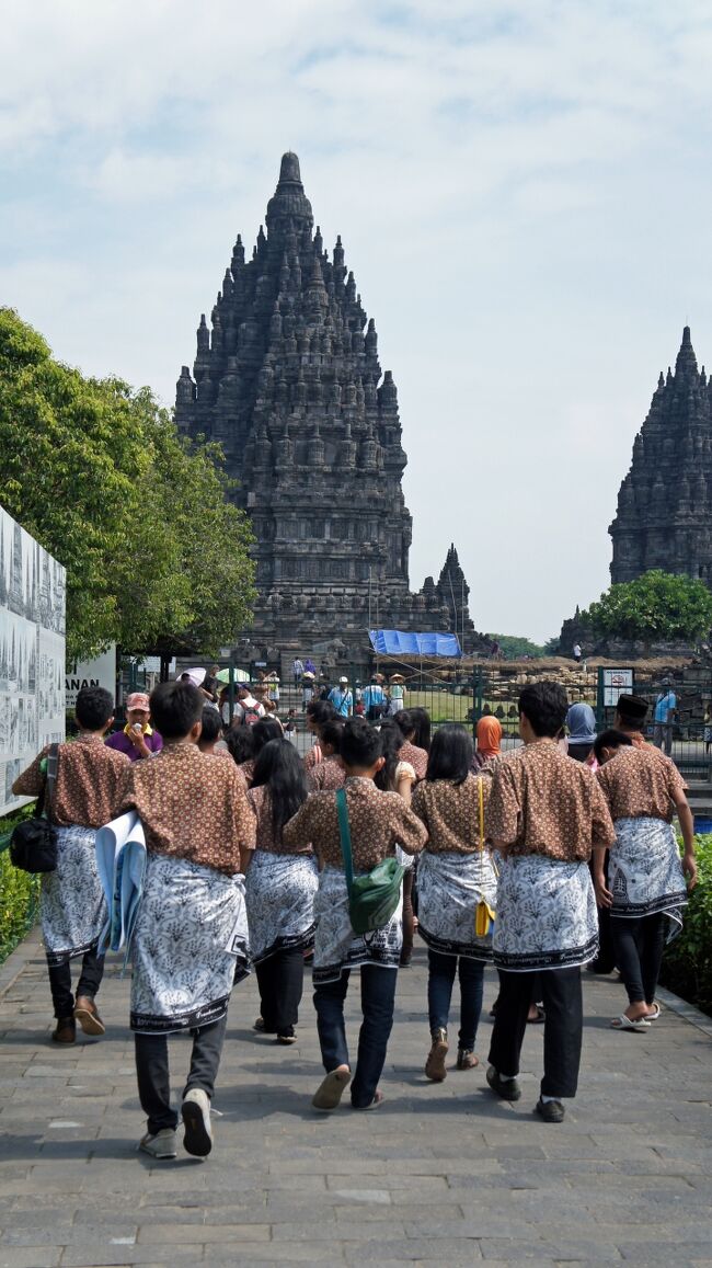 午前中にサンピ・サリとプラオサン寺院を廻っただけでプランパナン寺院に着くともう昼過ぎになっていました。駐車場でタクシーの運転手さんと別れ、いよいよロロ・ジョングラン寺院の見学です。外国人用の入り口で13ドル用意していたのですが、ルピアでしか支払えず料金は172,000ルピアでした。手持ちのルピアがピンチです。入口のゲート前で係の女の子がサルンを巻いてくれます。背中のザックにはバリ島で散々使った自分のサルンがありましたが、これを出したら自分で巻かないと駄目だろうなと思い、出しませんでした。遺跡公園に入ると木立の向こうにロロ・ジョグランの遺跡群が望めました。暑さはピークの時間帯のようで立っているだけでも汗が噴き出します。柵で囲まれたロロ・ジョングランの中には社会科見学なのか高校生の団体が沢山いましたが、敷地は広大なので見学で混み合う事はありませんでした。間近かで見る寺院はあまりに巨大で圧倒されました。一つ一つじっくり見学するとここだけで2時間はたっぷりかかりました。次にセウ寺院へ向かうべく汽車型の巡回バス乗り場へ向かいました。5,000ルピアを支払おうとするとチケット売り場のガラスに外国人無料と書かれてありました。セウ寺院では途中下車して5分間の写真撮影タイムがありました。乗り場のおじさんには途中下車すると話しておいたのですが、運転手さんには伝わっていなかったようで、心配されてバスはしばらく待ってくれていたそうです。妻が「次のバスで行きます。」と伝えて出発したそうです。一緒に乗っていた小学生たちごめんなさい。遺跡公園には他にも遺跡はありましたが修復工事中だったので、ロロ・ジョングランとセウの２つの見学は必須と思いました。どうしてもボロブドゥール遺跡が先に立ちますがプランパナン遺跡も劣らずに素晴らしい遺跡でした。