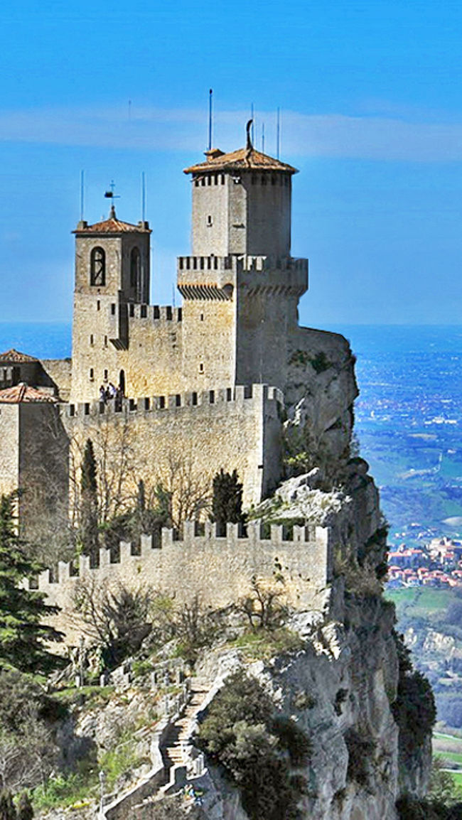 サンマリノ共和国(Republic of San Marino)<br /><br />最も高貴な共和国サンマリノは、イタリア半島の中東部に位置する共和制国家。首都は国名と同じくサンマリノ市。周囲は全てイタリアで、世界で5番目に小さな国(ミニ国家)である。また、現存する世界最古の共和国です。<br /><br />ボローニャから、快適な高速道路A14/E45号線を南東へ約2時間弱、途中リミニ(Rimini)のインターをSS72号線を右折れし10kmも走ればサンマリノ共和国へ入国。鉄道で入国する場合はボローニャ経由リミニ(Rimini)駅で下車、バスにてサンマリノ共和国へ向かいます。<br />入国にはパスポート等何も必要なく、突然中世のイタリアの田舎町に迷い込んだようだ。観光案内所に行って手数料を払うと、パスポートに入国スタンプを押してもらえます。 <br /><br /><br />標高749mの岩山ティターノ山頂にある首都サンマリノ市、イタリアの向側にアドリア海が遠望出来る。山頂には山麓からケーブルでも登る事が出来る。