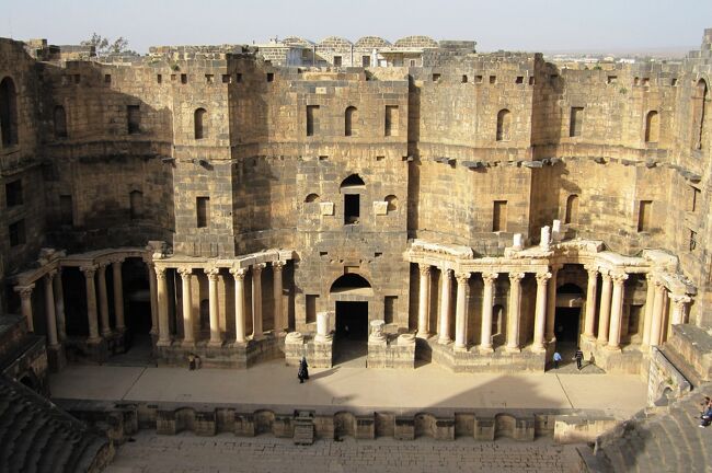 ボスラの世界文化遺産、ローマ劇場見学の続きです。古代ローマ時代の劇場としては、世界で三番目の規模とされます。ボスラは、シリアの首都ダマスカスの南約150キロ、ヨルダンとの国境近くに位置します。劇場の外観が黒っぽく見えるのは、使われている石材が玄武岩のためとされます。ボスラがローマ帝国のアラビア属州の州都となった時代の2世紀末、ローマ劇場はローマ人の手によって造られました。外観は、劇場と言うより、堅固な城郭のイメージでした。
