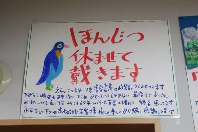 大阪市北区の中崎通商店街に「青空書房」という一軒の古本屋さんがあります。<br /><br />店主、坂本健一さんは、戦後間もなく結婚した和美さんと二人で「青空書房」を開店し、以来、半世紀にわたって年中無休で働いてこられましたが、10年前に脳梗塞で倒れたのを機に、毎週日曜日を定休日にしました。<br /><br />ところが、毎週日曜日が定休日になったことを知らずに訪ねて来るお客さんが居ることに気づき、これではわざわざ来てくれたお客さんに申し訳ないと、四季折々の風物誌や大阪の町の鼓動を伝える絵とともに、ピリッと風刺の効いた中にも、心暖かい気持のこもった言葉を添えた、坂本さん手描きの「ほんじつ休ませて戴きます」のお詫びのポスターを店のシャッターに貼るようになります。<br /><br />時に読書の素晴らしさを説き、時に人の温もりや人情の機微を失いつつある現代社会を憂おう坂本さんの言葉の底流には、「人に対する心温まる眼差し」とともに、平成22年2月5日にお亡くなりになられた和美さんへの想いと、ご自分への激励の意味も込められていて、多くの人々の共感を呼びます。<br /><br />今年の11月10日、いつものように店のシャッターに貼りだされた「ほんじつ休ませて戴きます」のポスターの下に、一枚の紙が添えられます。<br /><br />「永い間本当にありがとうございました 温かいお客様のおはげましと 古書への深い愛着が綴った六十七年 亡妻和美と苦闘と涙の歴史を閉じます」<br /><br />それは、これまでお店を支えてくれたお客さんに閉店を告げる貼り紙で、翌日、ご自身のブログにその写真を掲載すると、全国に波紋が広がり、坂本さんへの感謝の気持ちや閉店を惜しむメッセージが数多く寄せられます。<br /><br />また、このニュースは11月27日の新聞にも取り上げられ、「大阪・中崎町 青空書房 来年3月閉店」と報道されます。<br /><br />ところが、12月に入ると店横のドアに新たに紙が貼り出されます。<br /><br />「戦後六十七年 そのほとんどをこの店で 古本屋させて戴きました ひとえに本を愛し青空を愛して下さった お客様のお陰 心から 厚く厚く御礼申上げます 平成二十五年歳末閉店の止むなきに至りました 晩年味わふ挫折と徒労感 正に痛恨の極みです」<br /><br />それは、来年3月末閉店の予定を繰り上げ、年末に閉店するやむなきに至ったことを告げるものでした。<br /><br />「店におったら生き生きする。 休日になったら廃人ですわ。」と言ってはばからない坂本さんの胸中を察すると、さぞ無念だろうなと思うとともに、坂本さんの言葉に共感し、感動し、励まされた者の一人として、「長い間お疲れさまでした。」と長年の労をねぎらう気持ちがわき上がって来ます。<br /><br />そんな中、『「ほんじつ休ませて戴きます」ポスター展 〜大阪古書店主のメッセージ〜』と題する坂本さんのポスター展が、12月20日と21日の二日間、大阪古書会館6Fで開催されたので見に行ってきました。<br /><br />展示会の会場へ向かう前に中崎通商店街のお店を訪ね、いつものようにお元気な坂本さんの姿を見つけると、しみじみ寂しさがこみ上げてきます。<br /><br />やもたてもたまらず、「いつまで営業されるんですか?」とお伺いすると、「師走まで」との返事。<br /><br />「師走まで」・・・。<br /><br />まさかと思いながら「12月31日までですか?」と聞きなおすと、「そうです」と満面の笑みを浮かべた顔でうなづきます。<br /><br />事ここに及んでも、商人としてのけじめを貫こうとする坂本さんの姿がそこにありました。<br /><br />閉店されたら、まずゆっくりして下さい。<br />そして、体に気をつけて、いつまでもお元気で。<br /><br />坂本さんの言葉を人生の糧にして、これからも生きて行きます。<br />ほんとうにありがとうございました。