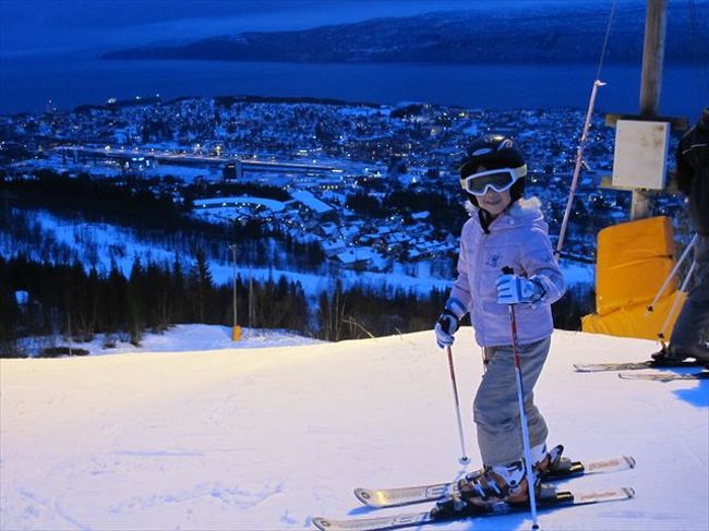 第3回北欧オーロラ紀行vo.3。スウェーデンのストックホルムから夜行寝台ノーランストーグで北極圏に入りノルウェーのナルヴィークに到着しました。クリスマスシーズンでどこも休日なのは前回と同じでしたが、出発前からスキーができることがわかっていたので、家族4人で歩いてスキー場へでかけました。北極圏なのでオーロラを期待してのスキーです。この写真は下の娘。2年生です。ナイタースキーのようですがもちろん昼間です！