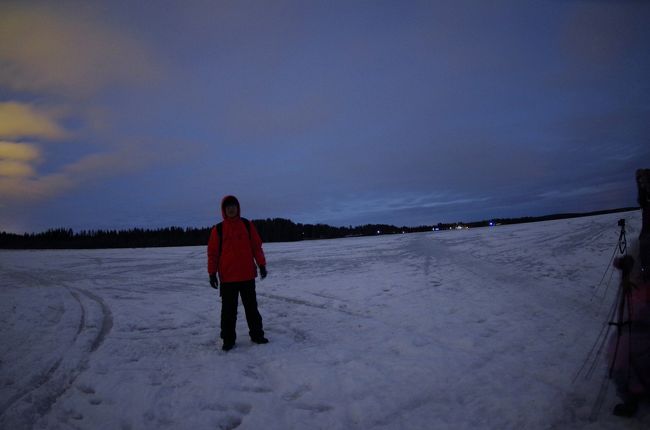 はっきりしたオーロラに遭遇できず、今度こその期待を持って臨んだオーロラ・ハンテイング。今回は日系エージェントということで、同行者はすべて日本人。現地ガイドの説明も当然日本語。我がツアーの同行おば様方もホットしています。<br />だが、しかし、ホテルを出発するときは粉雪が降っており、夜空はまったく何も見えない。僅かな望みを持って、ロヴァニエミの中心から郊外へと次第に高度を上げながらバスはとある湖に面したトナカイ牧場に到着。雪は止んだが、風も弱く、雲を吹き飛ばすことはなかった。<br />この編では曇りの夜空と氷の湖の写真だけです。<br />地上の遠くの街の灯りが雲に投射された景色だけとなりました。<br /><br />表紙はあきらめポーズの私、凍った湖の上でのアリバイ写真。ｉｓｏ８００で１０秒以上露出。肉眼ではほぼ真っ黒なシルエットとしか見えません。