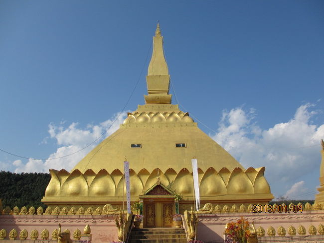 ルアンナムター博物館の外に出ると、前方の丘の上に金色に輝くパゴダが見える。パゴダはミャンマー語だからここでは「チェデイ」（&#3648;&#3592;&#3604;&#3637;&#3618;&#3660; ）と言った方が良いかも知れない。町の小高い丘の上に仏跡、仏塔があるのは、ウドムサイ同様で、この博物館からはそう遠くもなく、行ってみることにした。<br /><br />綺麗に区画整備された道路を歩き丘に向かう。学校があったり、高級な個人の住宅があったりと、この町の金持ち層が住んでいるような街区を通り抜け、丘の麓辺りに来ると、大分生活レベルが低そうな家屋なども見えて来て、自宅周辺には放し飼いのニワトリなどもいて、ラオスらしい長閑な光景だ。<br /><br />１００ｍにも満たない小山だが、登るに連れて視界が開けて来て、ルアンナムターの町が眼下に見え出してくる。タイやラオスの町では大体どこでも言えることだが、この町も緑が濃い。緑の中に住宅が建っている、と言った感じにも見える。日本のような猫の額ほどの狭い敷地に住宅が立ち並んでいる、建て込んでいる、と言った情景とは全く反対の都市景観だ。<br /><br />丘の上にはまだできて間もないと思われる金色に輝く仏塔が建っていた。随分と大きな仏塔だが、参詣客の姿は見えない。高校生か大学生のような男女が数人バイクでやってきて、木陰で休んでいる程度の静けさだ。だから線香の煙も漂ってこない。境内の敷地はまだ完成されてなく、整備が現在進行中のようだが、工事人の姿も見えず、この状態で放置か、一時停止されているようだ。人件費予算が続かなくなったのか・・。<br /><br />仏塔は内部に入れる構造になっているが、今は入口のドアが施錠されていて、入ることはできない。ふと見ると入口の横に沢山の小旗と人形のようなものが置かれている。つい最近何かの祭礼があったようだ。仏塔をぐるりと一周する。円周は５０ｍ程か。かなり大きなチェデイだ。ルアンナムターは精々２−３万人程度の人口もそれ程多くない小都市だが、これだけ立派な仏塔を作るのに、住民の負担も大きかったに違いない。人々は貧しくても、沢山の寄進（&#3607;&#3635;&#3610;&#3640;&#3597;・タンブン）をする。タイ、ラオス、カンボジア、ミャンマーに共通する人々の宗教心だ。<br /><br />